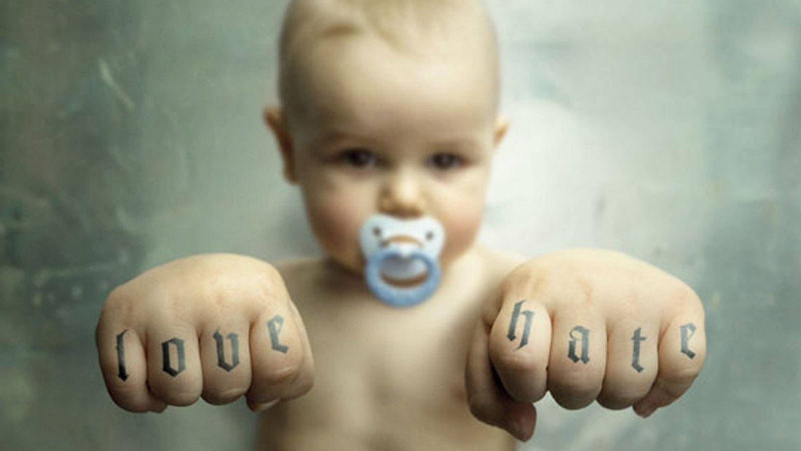 Funny Baby 桌布 壁紙 — 一個戴著奶嘴的嬰兒舉起拳頭，拳頭上用哥德字體紋有love和hate字樣。