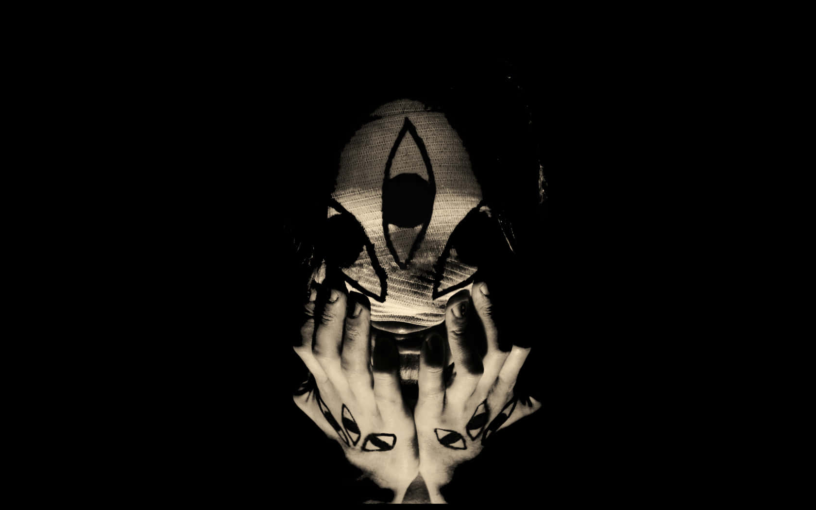 Occult 桌布 壁紙 — 一個戴著幾何面具並有匹配手部刺青的人，在黑暗中捧著自己的臉。