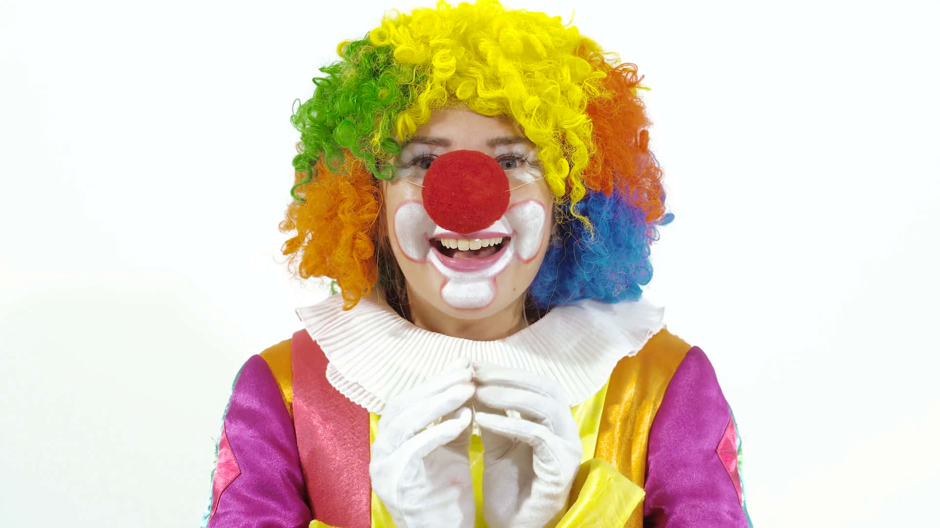 搞笑 桌布 壁紙 — 一個戴著彩虹假髮和紅鼻子的快樂小丑，在純白背景上燦爛地微笑。
