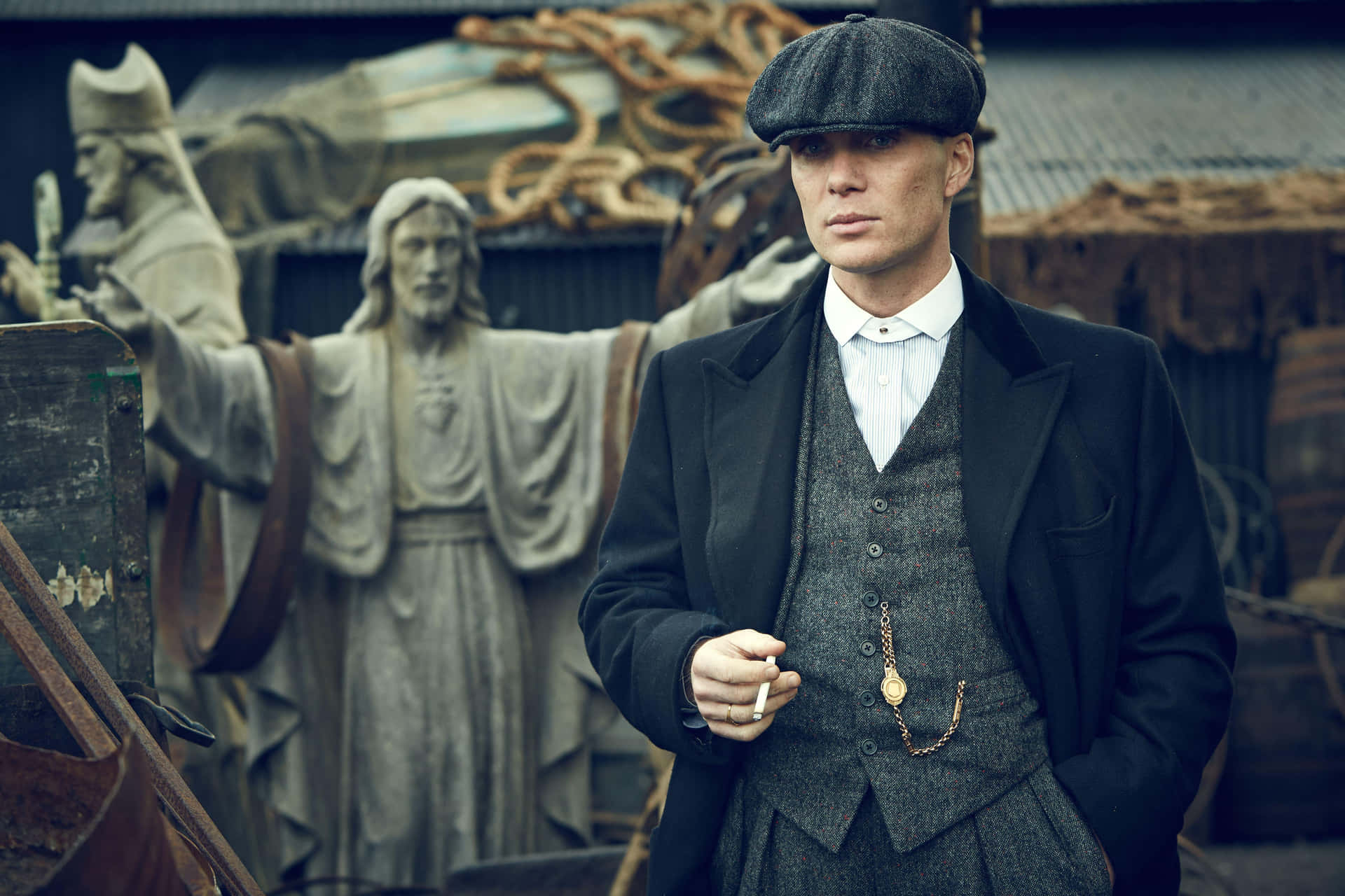 身穿復古西裝和帽子的男人在石像附近拿著煙。 — Peaky Blinders 壁紙