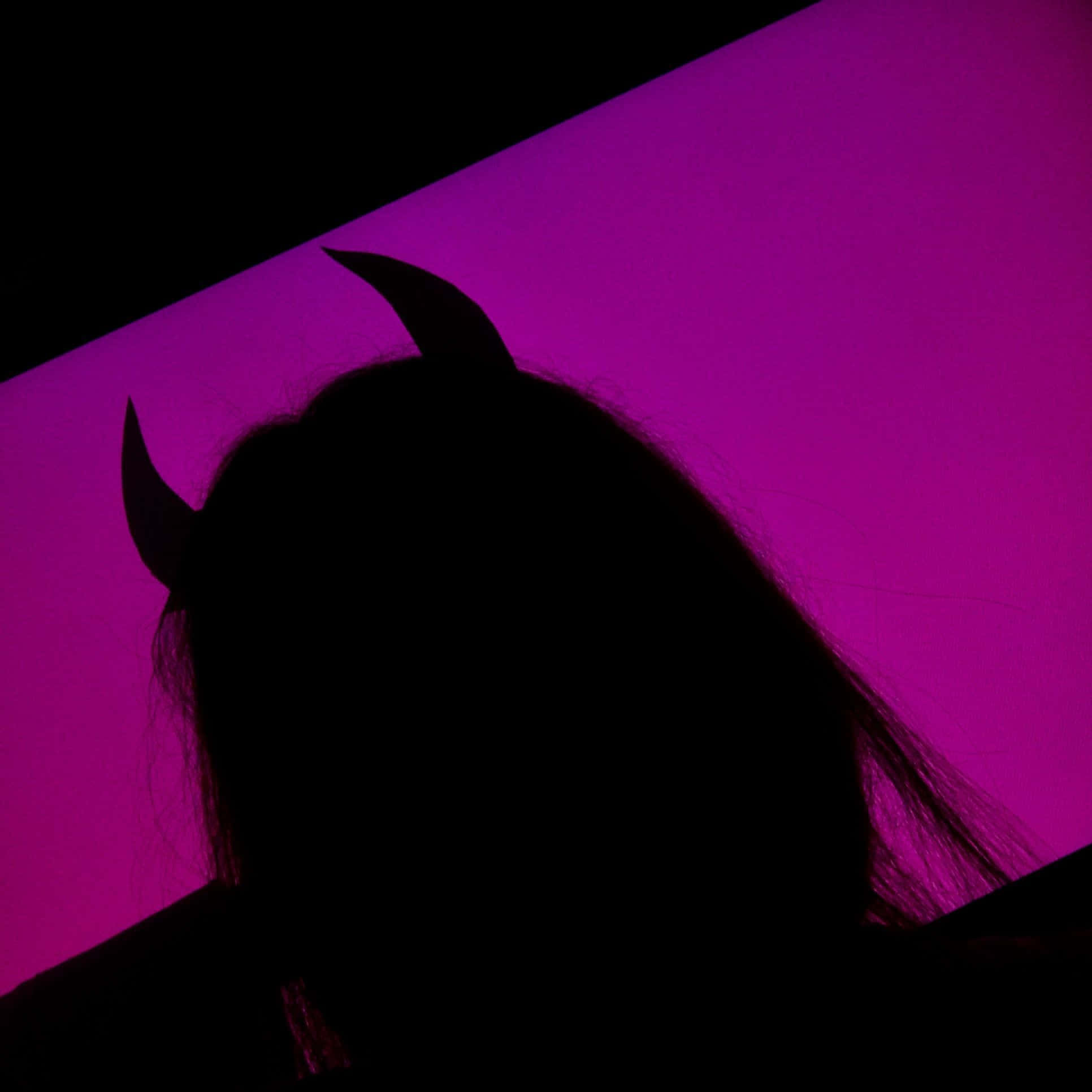 桌布 壁紙 — 一個戴著惡魔角的人影，襯托著充滿活力的紫色燈光背景。