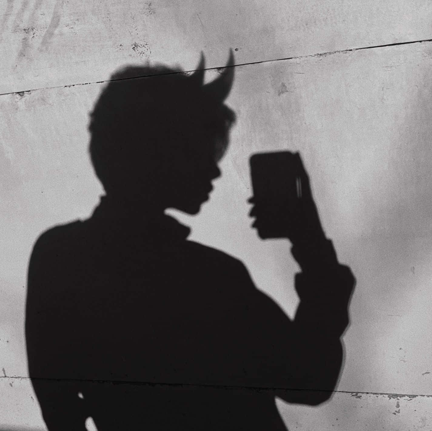 reflection 桌布 壁紙 — 一個戴著惡魔角的人的清晰黑色影子在風化的混凝土牆前自拍。