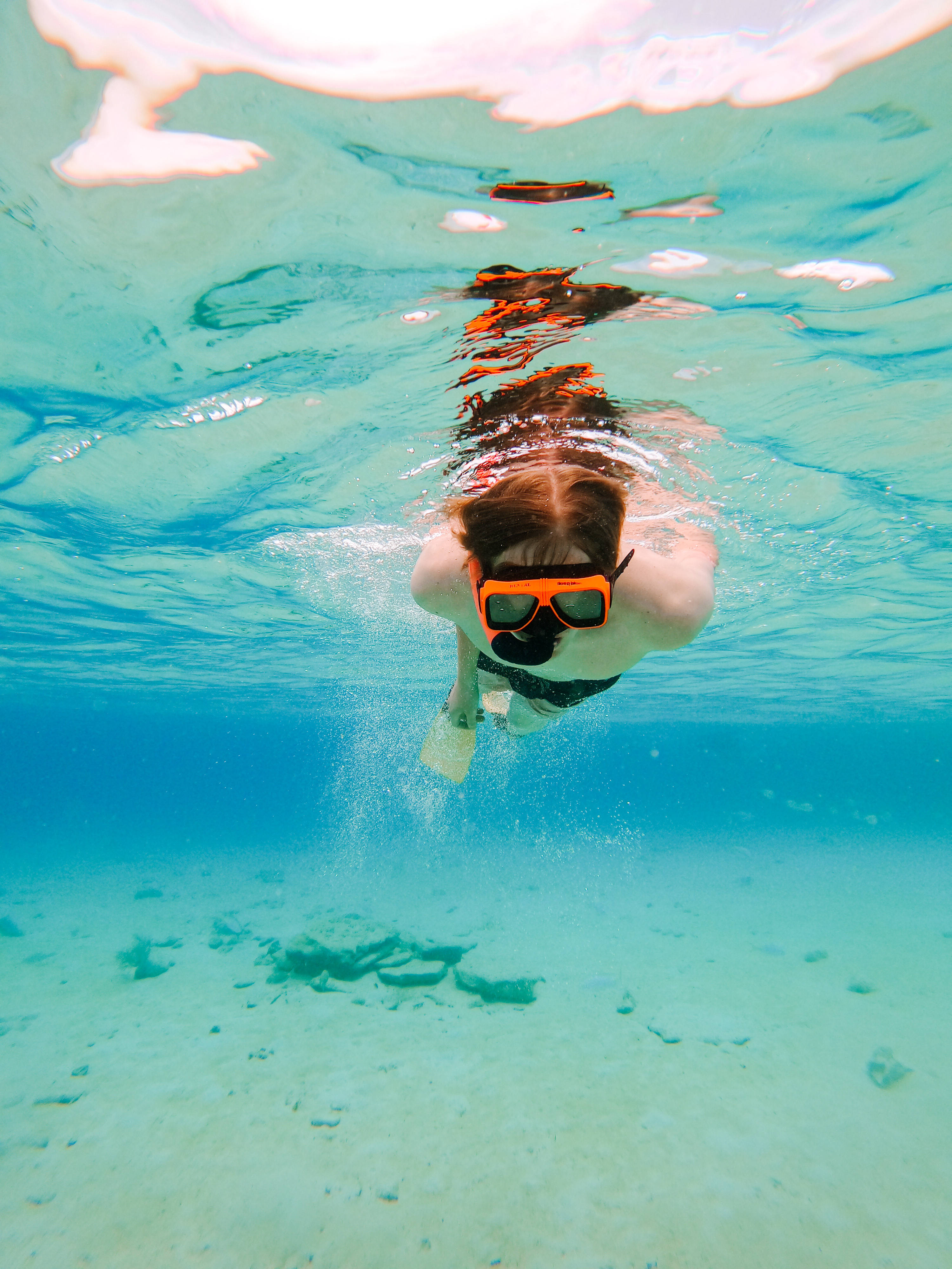 Snorkeling 桌布 壁紙 — 一個戴著橙色潛水裝備的人在水底清澈的藍綠色海水中游泳，下方是沙質海床。