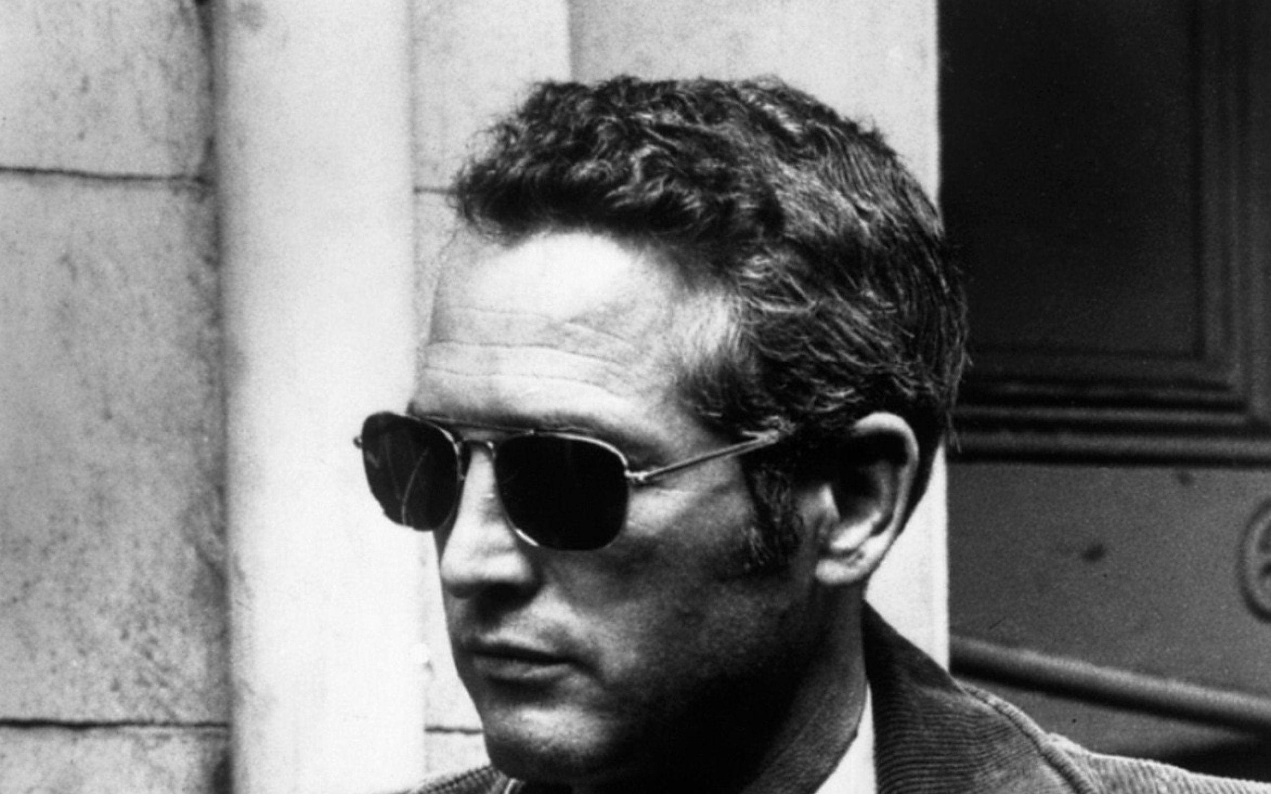 newman 桌布 壁紙 — 一個戴著深色太陽眼鏡和捲髮的男人站在石柱附近的黑白肖像。