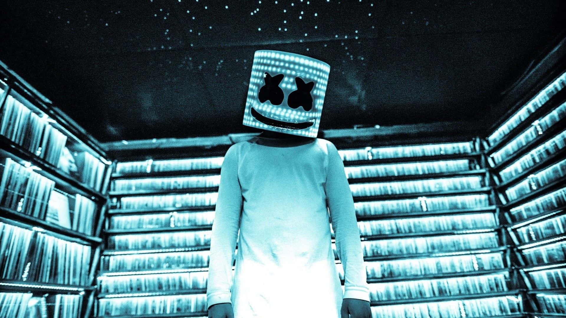Marshmello 動態圖 桌布 壁紙 — 一個戴著發光笑臉面具的人物站在一個滿是星星的房間裡，周圍是發光的書架。