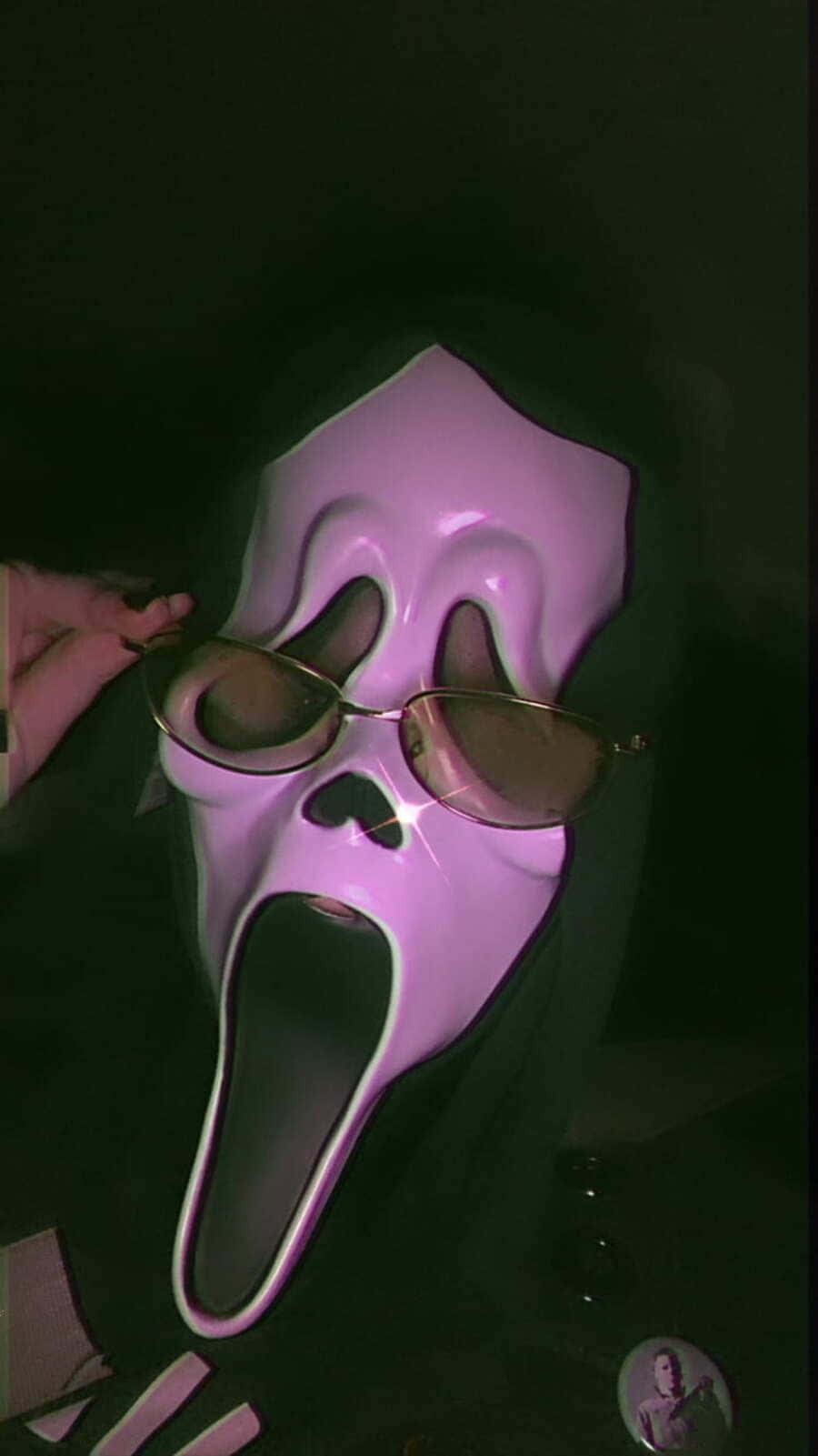 Ghostface Aesthetic 桌布 壁紙 — 一個戴著發光紫色Ghostface面具的人，在黑暗背景下戴著金邊太陽眼鏡。