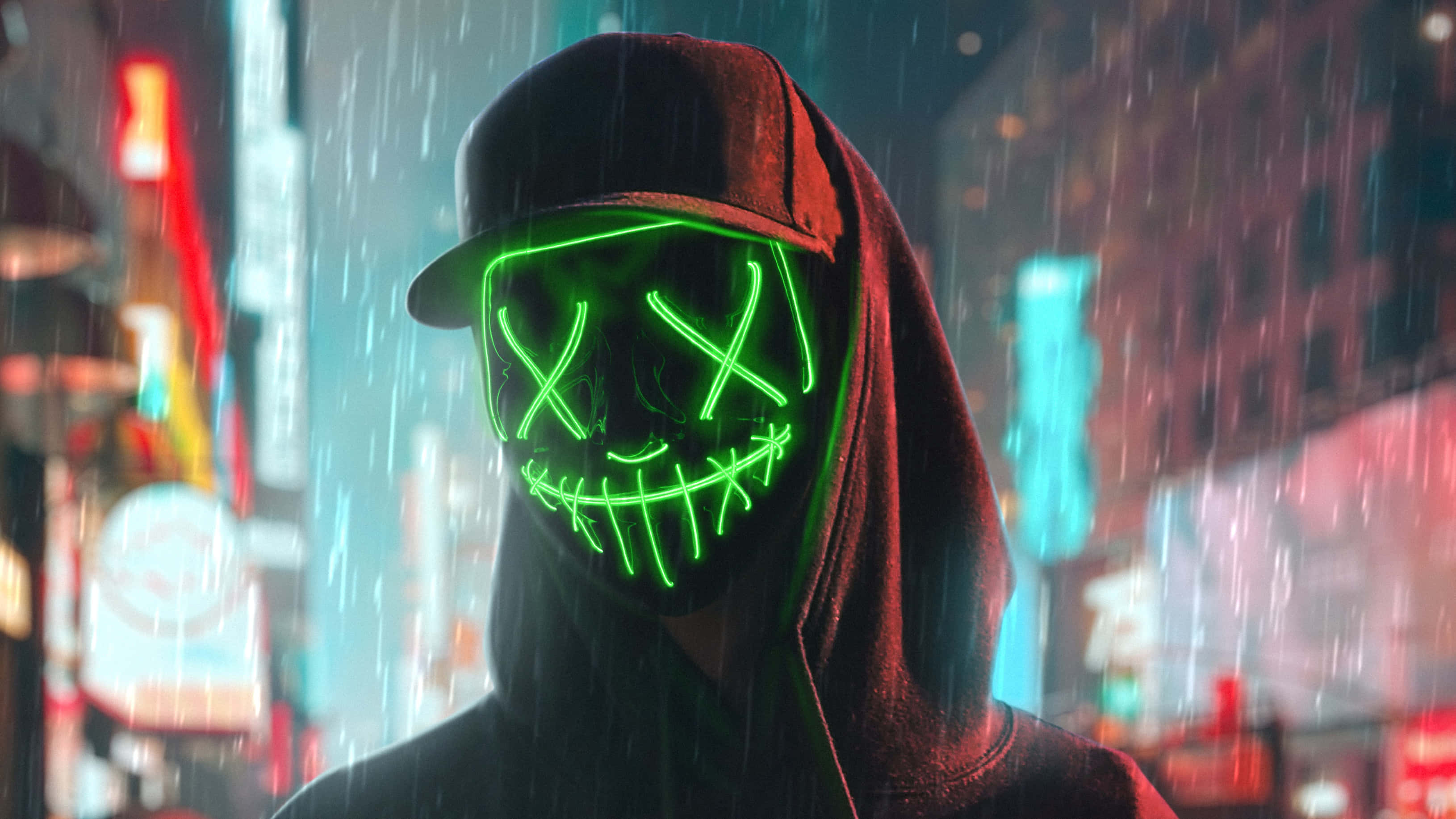Mask Boy 桌布 壁紙 — 一個戴著發光綠色霓虹面具的兜帽人物，站在雨濕的城市街道上，周圍是鮮豔的霓虹燈。