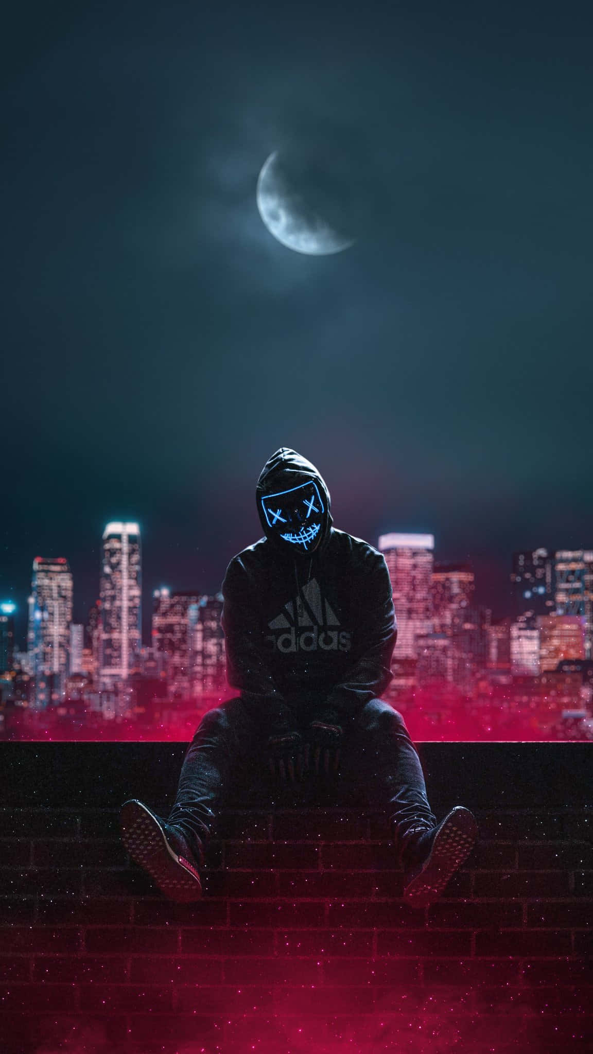 Mask 桌布 壁紙 — 一個戴著發光藍色骷髏面具的兜帽身影，坐在磚砌邊緣上，背景是新月下霓虹閃爍的城市天際線。