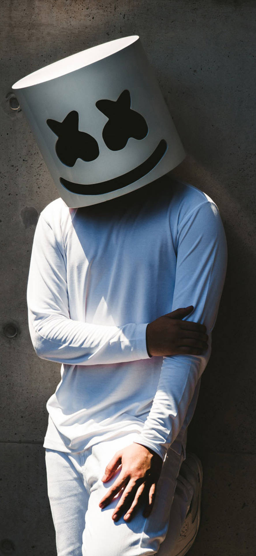戴著Marshmello頭盔的人穿著白色衣服靠著混凝土牆。 — Marshmello 動態圖 壁紙
