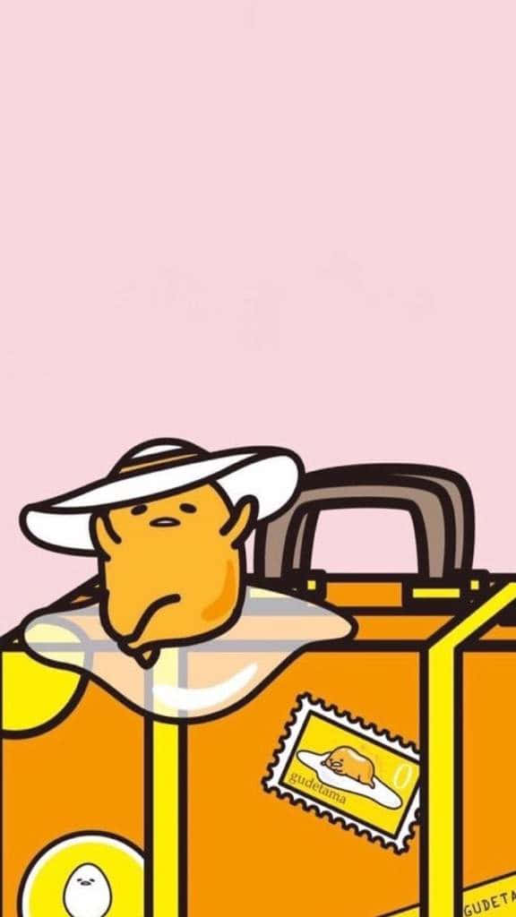 Gudetama Aesthetic 桌布 壁紙 — 一個戴著白色帽子的可愛黃色卡通角色，從一個亮橙色的行李箱中探出頭來，背景是柔和的粉紅色。
