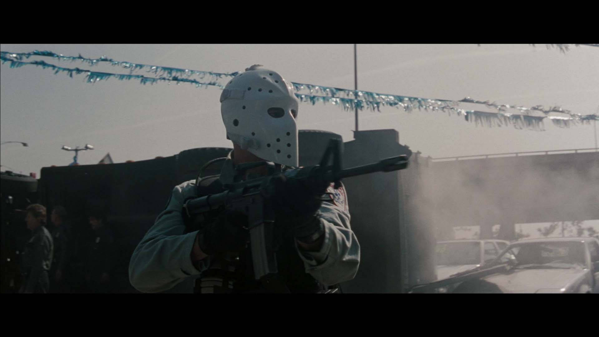 Action 桌布 壁紙 — 一個戴著白色曲棍球面具的人物在荒涼的停車場中，在煙霧和藍色閃粉之間手持步槍。