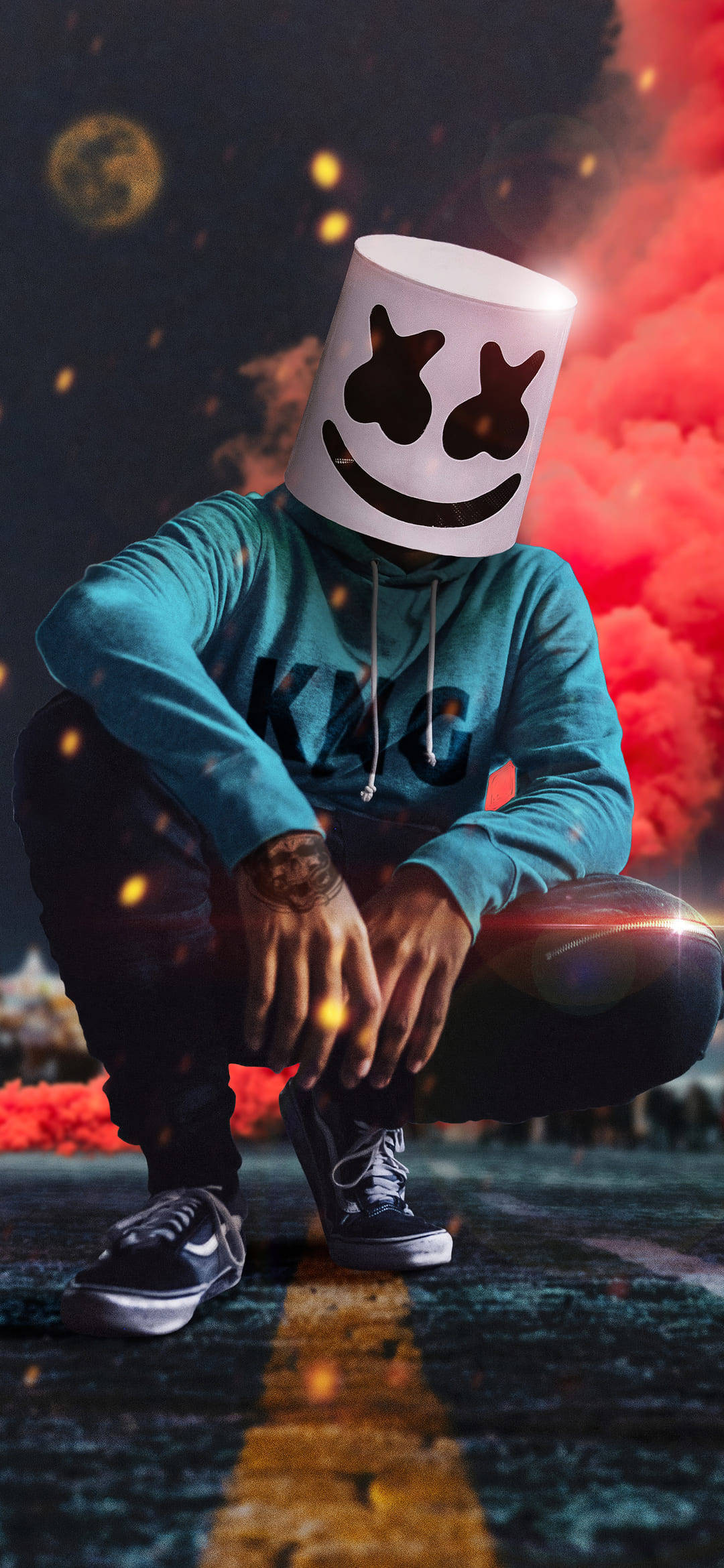 Marshmello 動態圖 桌布 壁紙 — 一個戴著白色棉花糖面具的人蹲在路上，周圍有火紅色的煙霧和發光的粒子旋轉。