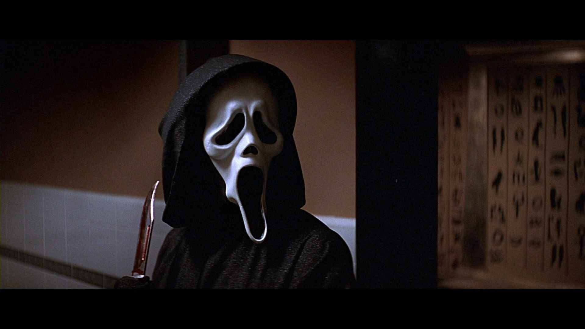吶喊 桌布 壁紙 — 一個戴著白色鬼臉面具和黑色連帽衫的人物，在昏暗的浴室裡拿著一把沾血的刀。
