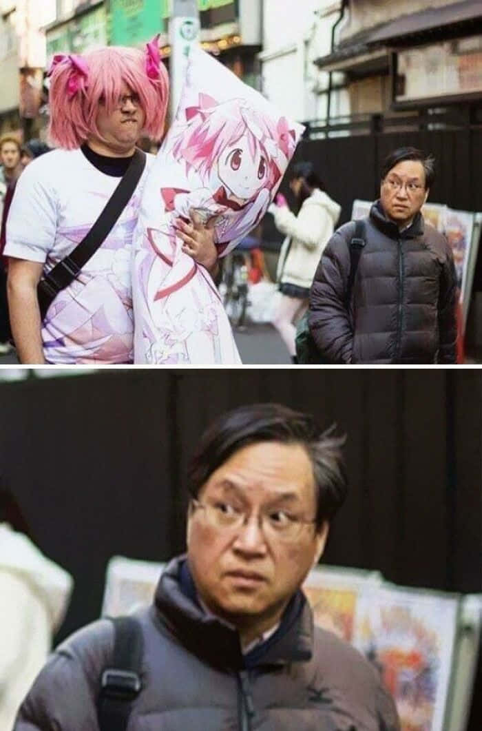 meme 桌布 壁紙 — 一個戴著粉紅色假髮、穿著動漫服裝的人，在繁忙的城市街道上行走，抱著一個大型角色抱枕。