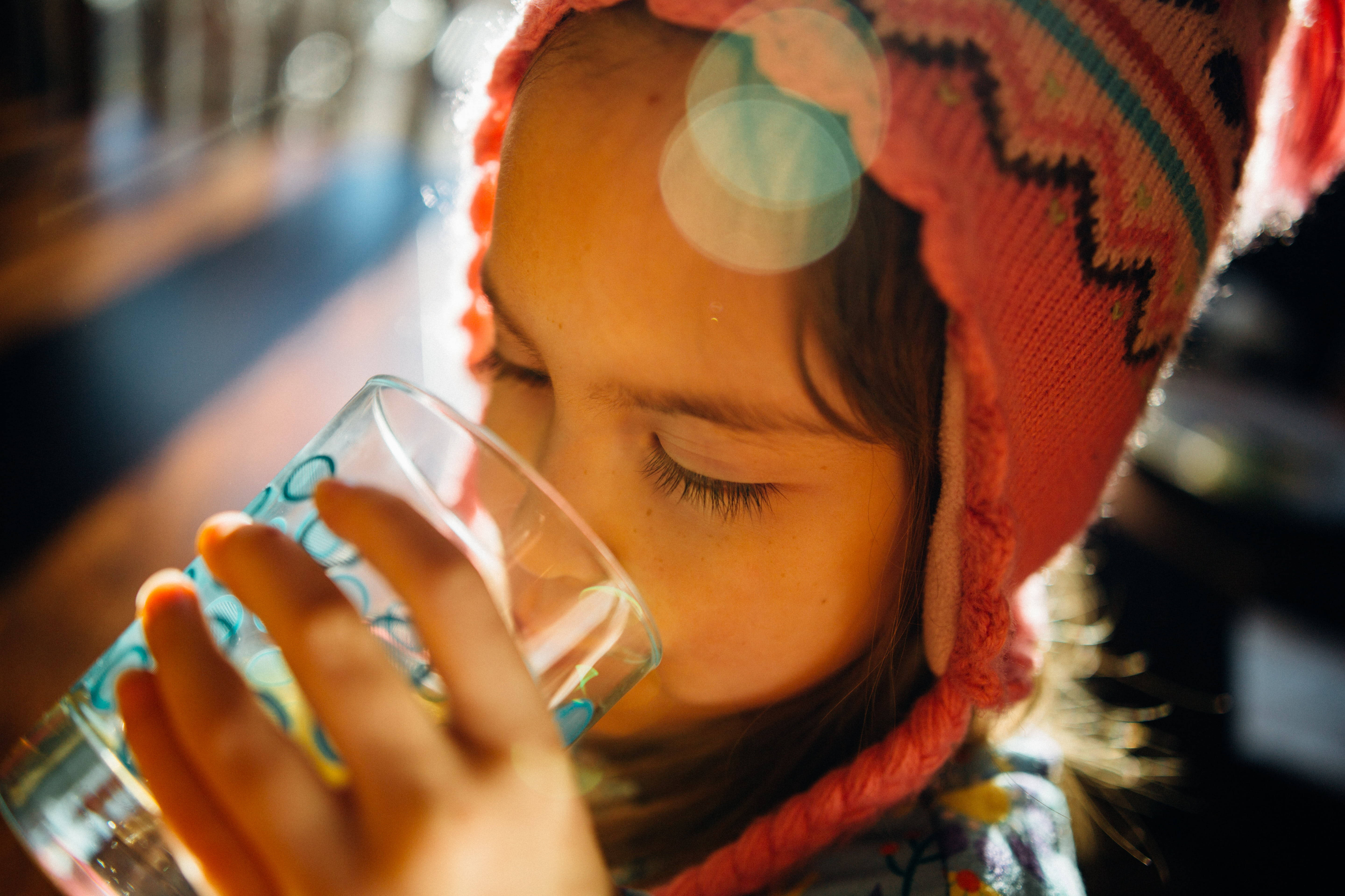 Drinking 桌布 壁紙 — 一個戴著粉紅色針織帽的小女孩，閉著眼睛靜靜地專注地喝玻璃杯裡的水。