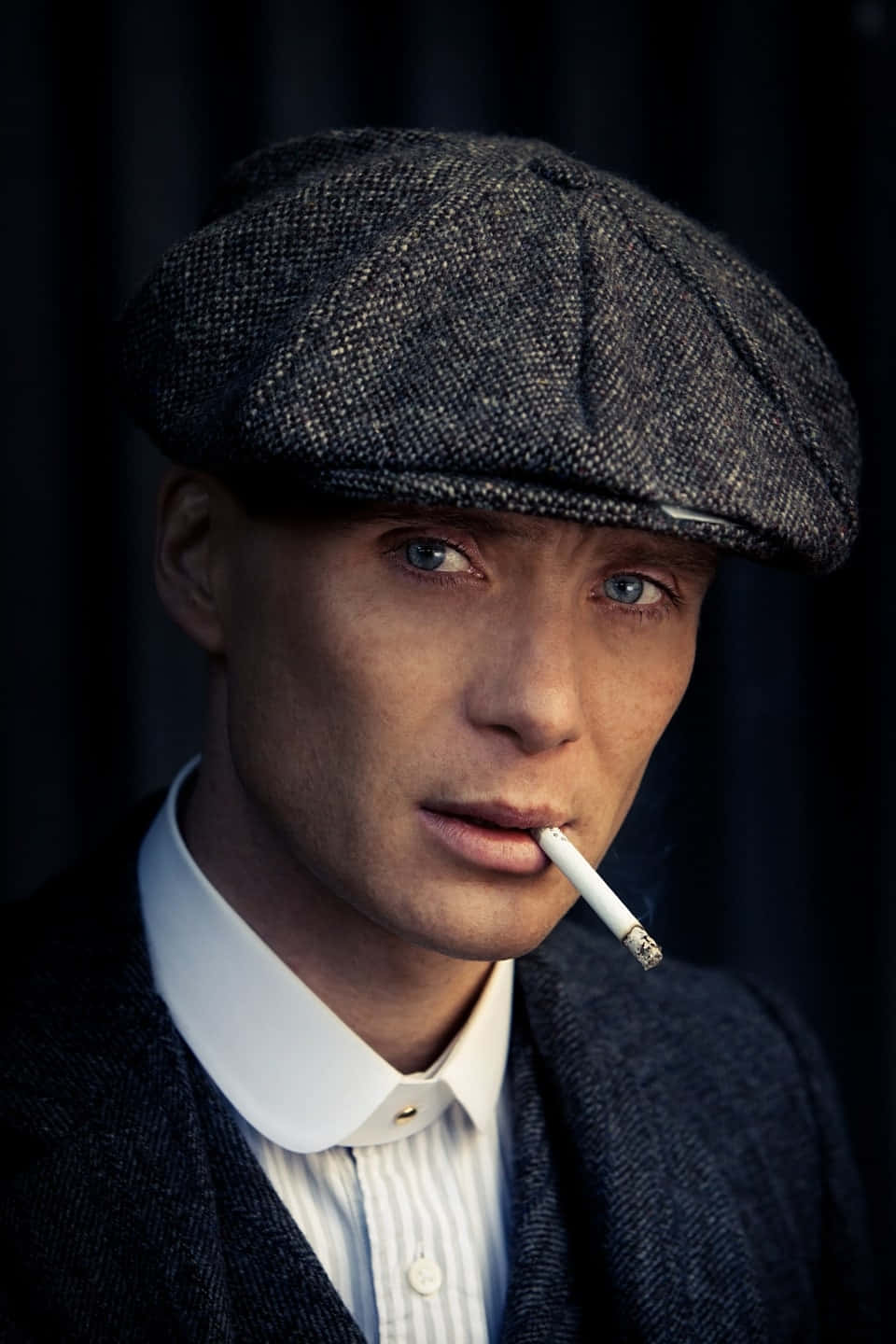 戴平頂帽和西裝的男人，眼神銳利地拿著香煙。 — Peaky Blinders 壁紙