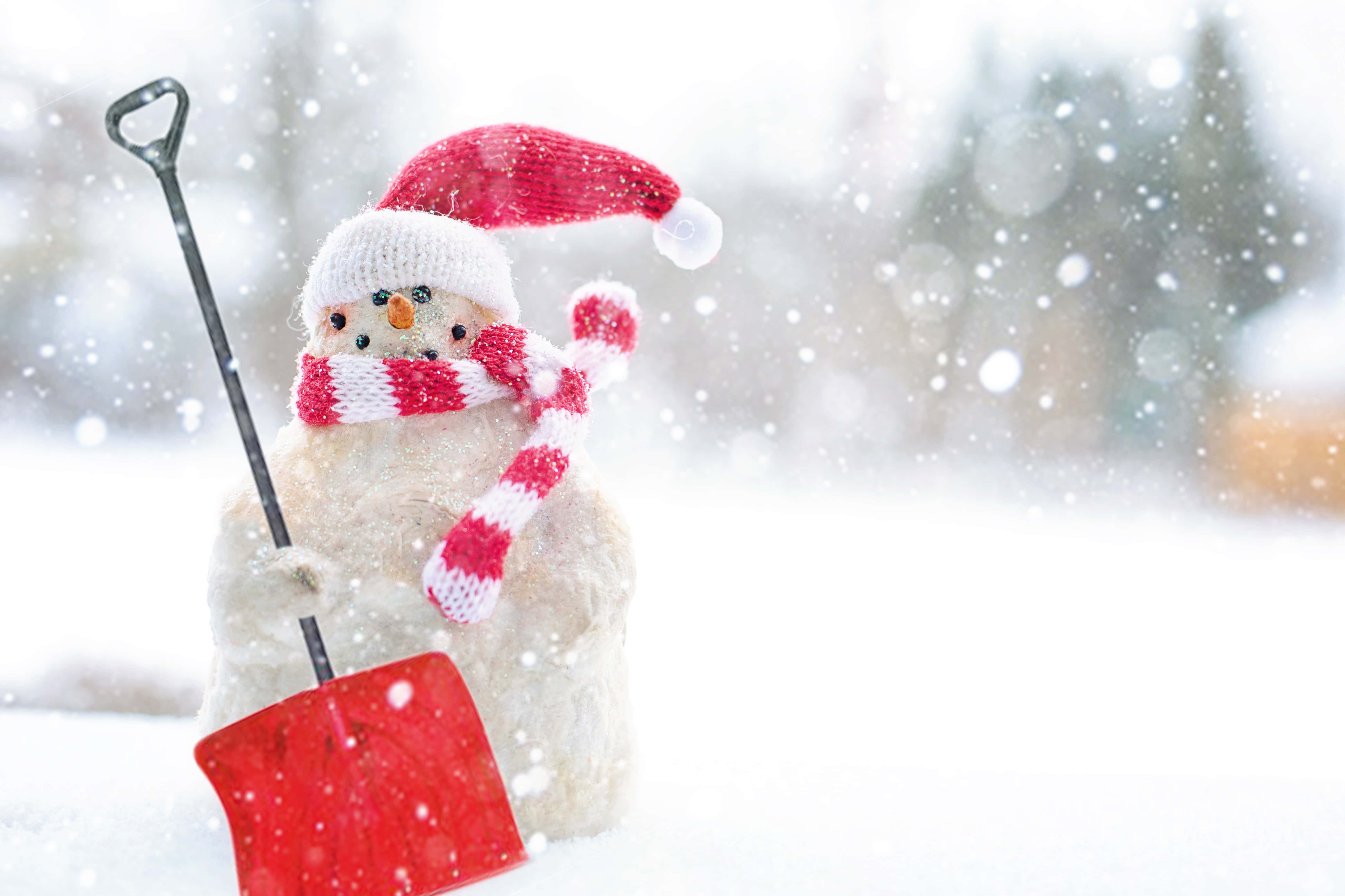 Christmas Snow 桌布 壁紙 — 一個戴著紅帽子和條紋圍巾的快樂雪人，在冬日場景中雪花飄落時拿著一把紅色鏟子。