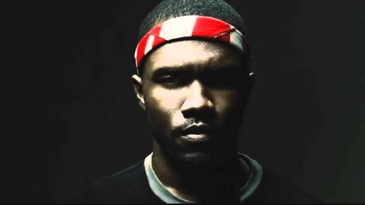 Frank Ocean 桌布 壁紙 — 一個戴著紅白頭帶的男人在黑暗背景和戲劇性燈光下強烈凝視。