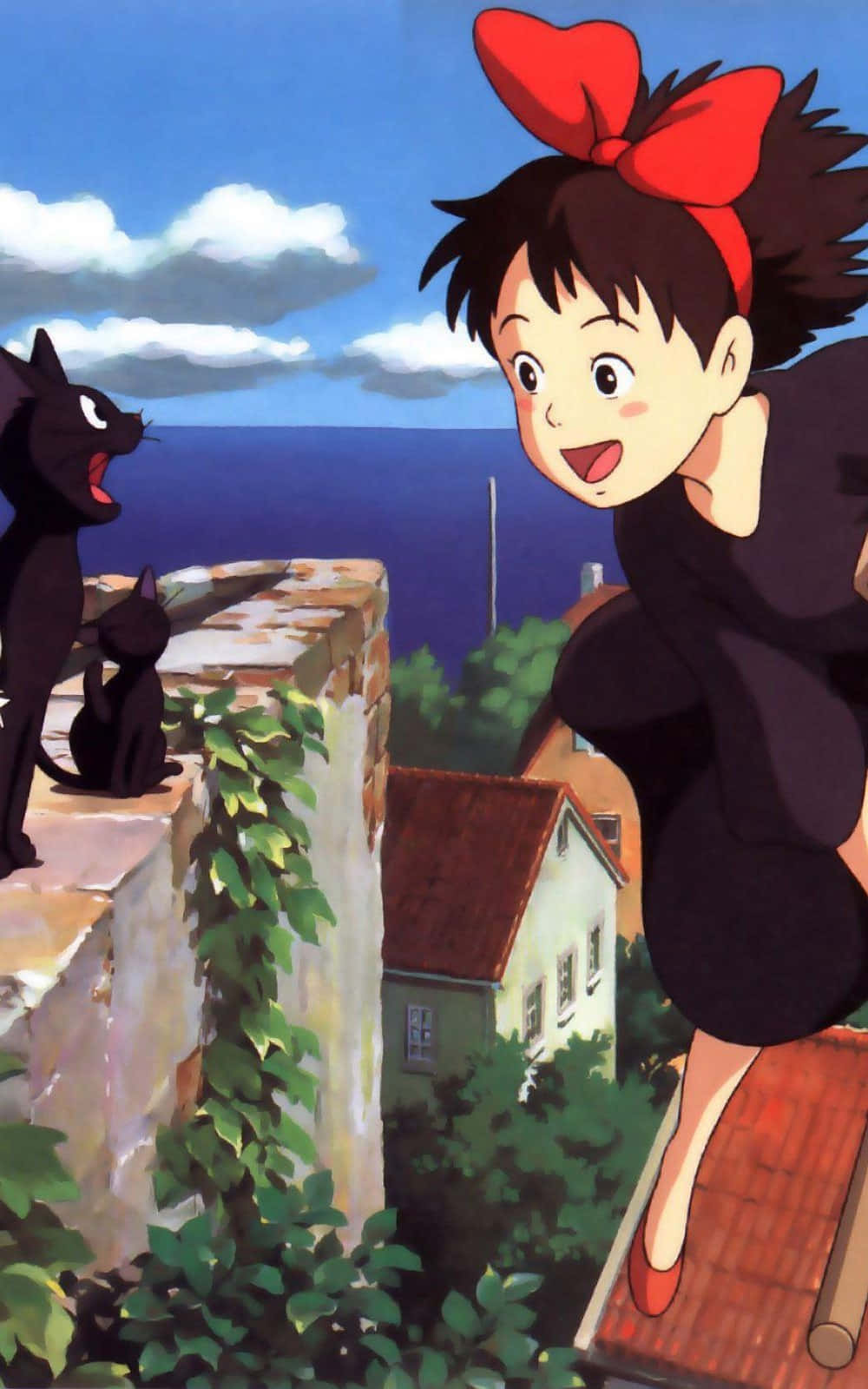 Jiji Cat 桌布 壁紙 — 一個戴著紅色蝴蝶結的開朗動畫女孩，在一個俯瞰沿海城鎮、爬滿藤蔓的屋頂上，快樂地跳躍在兩隻黑貓旁邊。