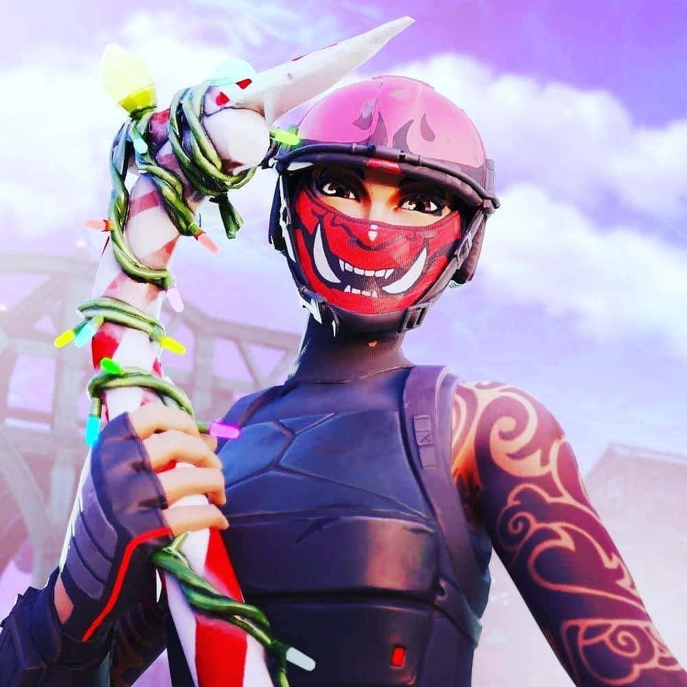 Mask 桌布 壁紙 — 一個戴著紅色面具和粉紅色頭盔的Fortnite角色，在紫色天空下拿著一根用綠色藤蔓和彩色燈光包裹的拐杖糖。