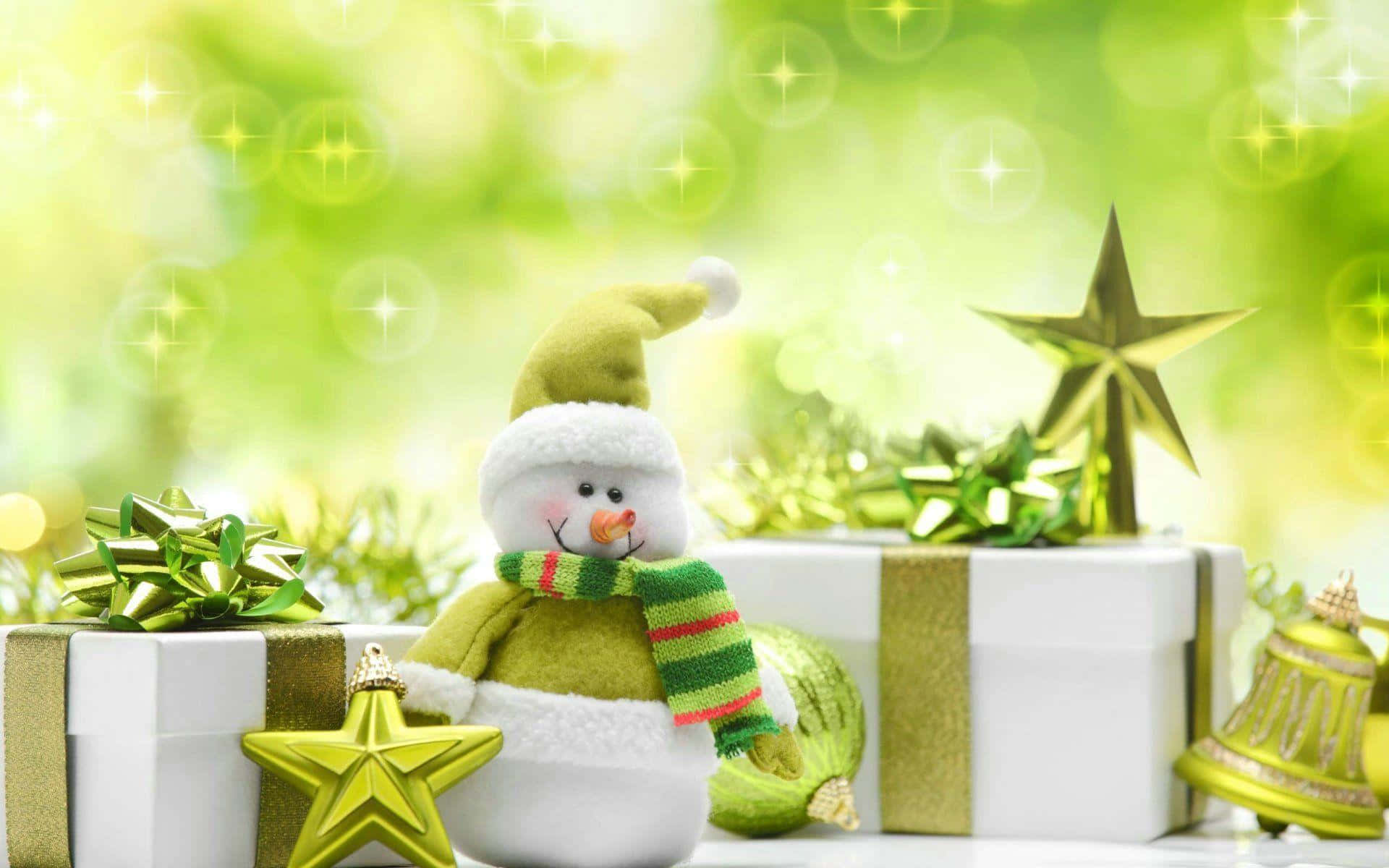 聖誕節 桌布 壁紙 — 一個戴著綠色帽子和條紋圍巾的快樂雪人公仔，坐在白色禮物盒旁邊，禮物盒飾有金色蝴蝶結和星星，背景是閃爍的綠色散景。