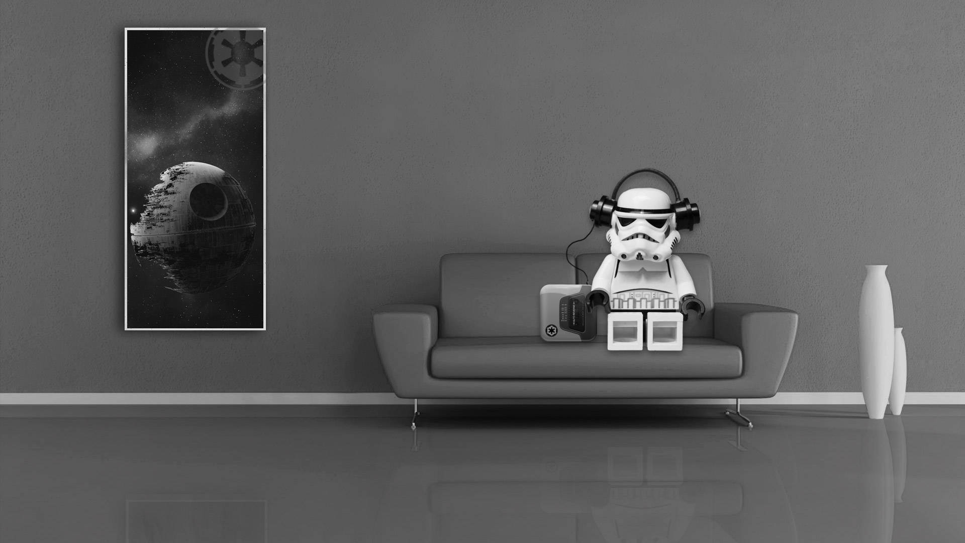 Lego Star Wars 桌布 壁紙 — 一個戴著耳機的LEGO風暴兵坐在現代灰色沙發上，旁邊有一張死星海報，在一個極簡主義的單色房間內。