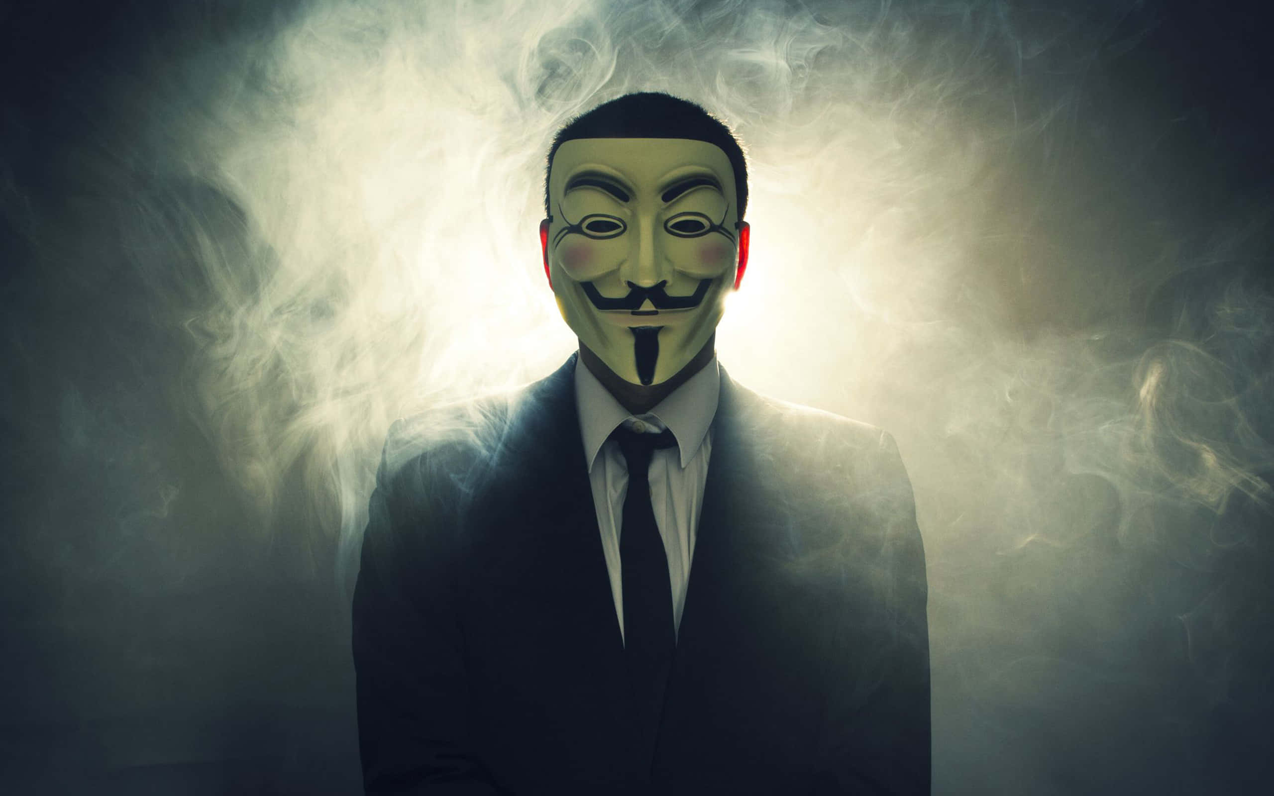 匿名 桌布 壁紙 — 一個戴著蓋伊·福克斯面具和西裝的人，在黑暗環境中背光照射，背景是旋轉的煙霧。