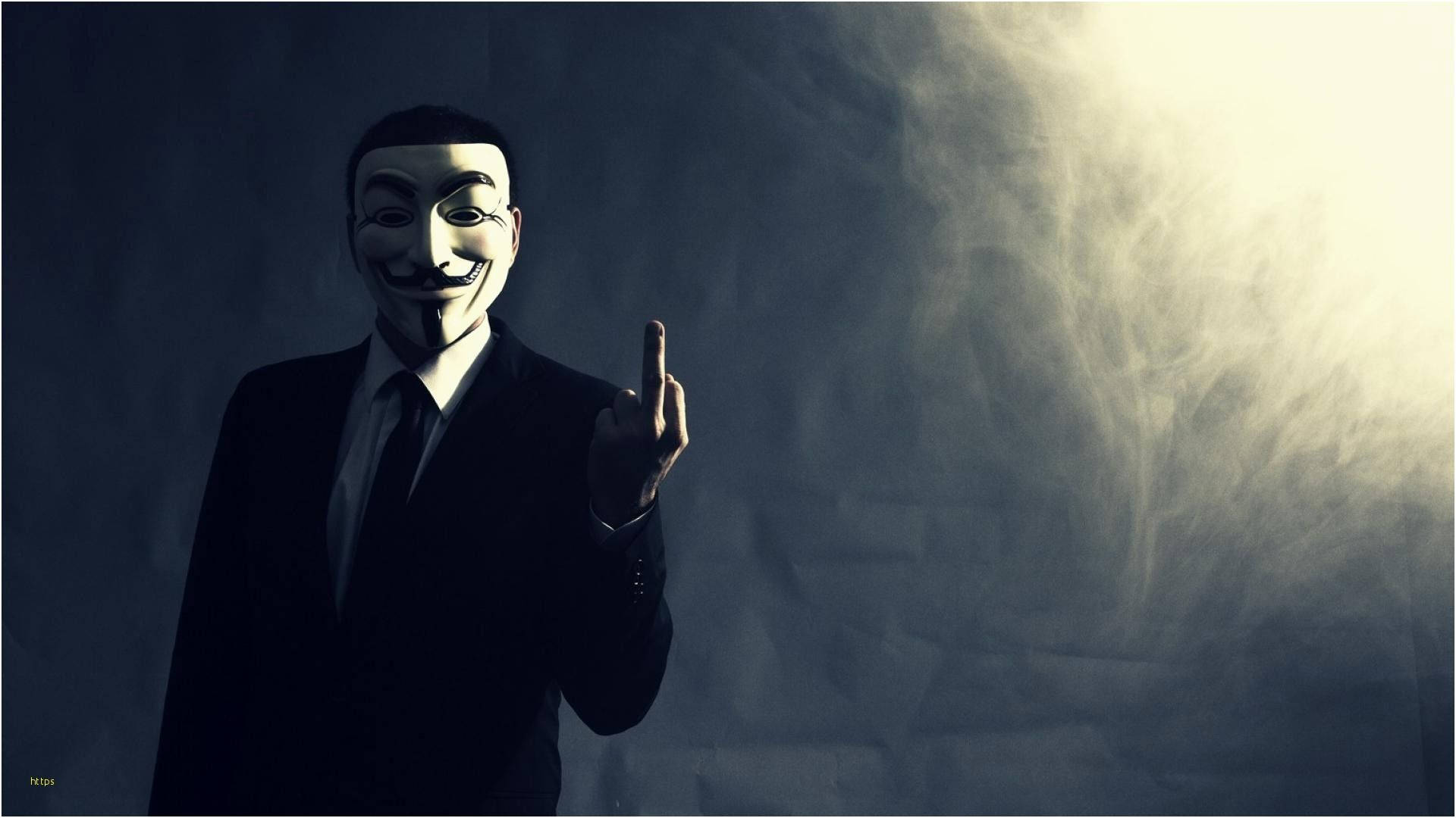匿名 桌布 壁紙 — 一個戴著蓋伊·福克斯面具和西裝的人，在煙霧繚繞的背景前，被戲劇性的背光照亮，挑釁地豎起中指。