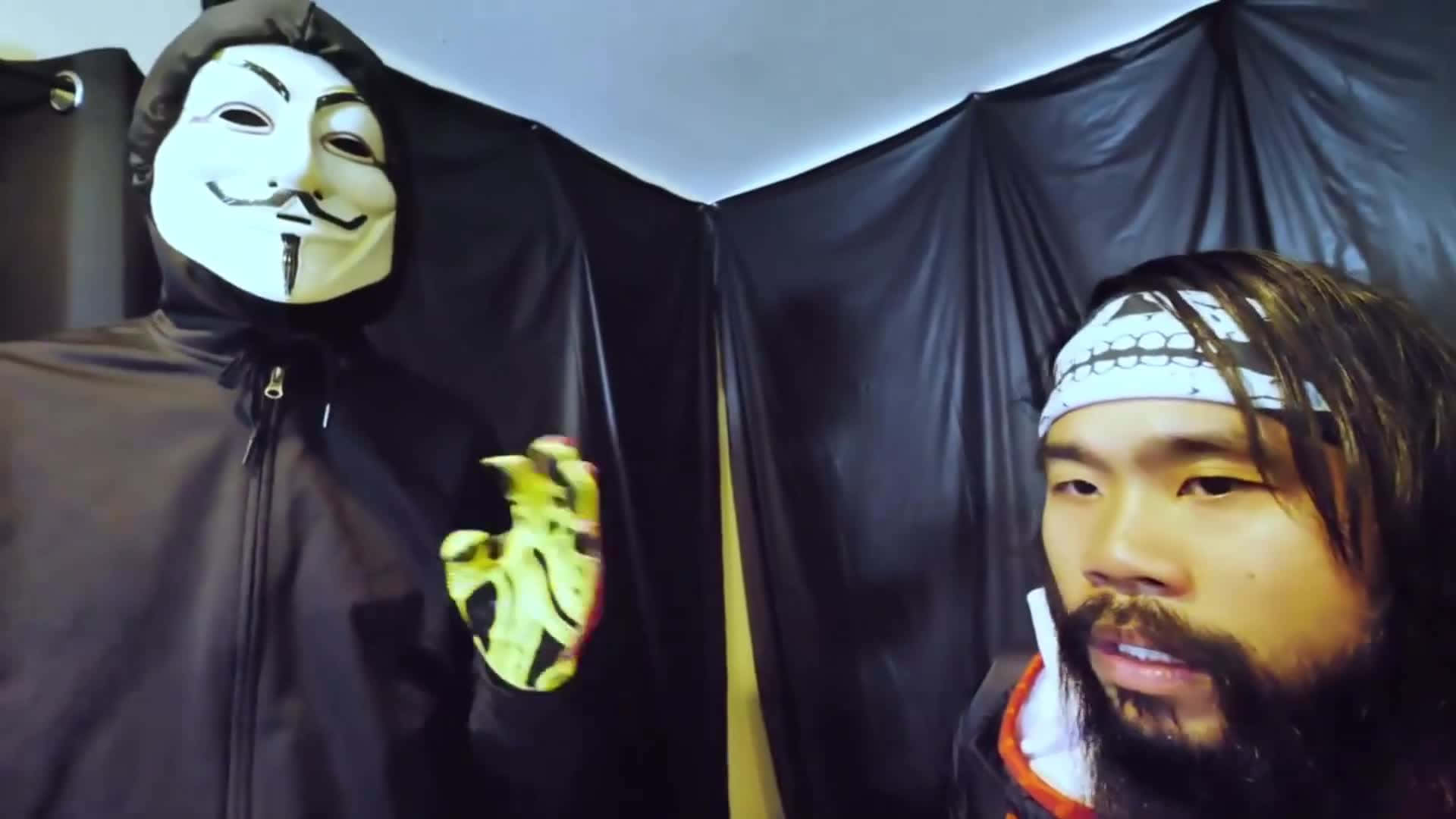 Man 桌布 壁紙 — 一個戴著蓋伊·福克斯面具的人拿著一顆發光的心臟，而一個留鬍子、戴頭帶的男人在黑色窗簾前看著。