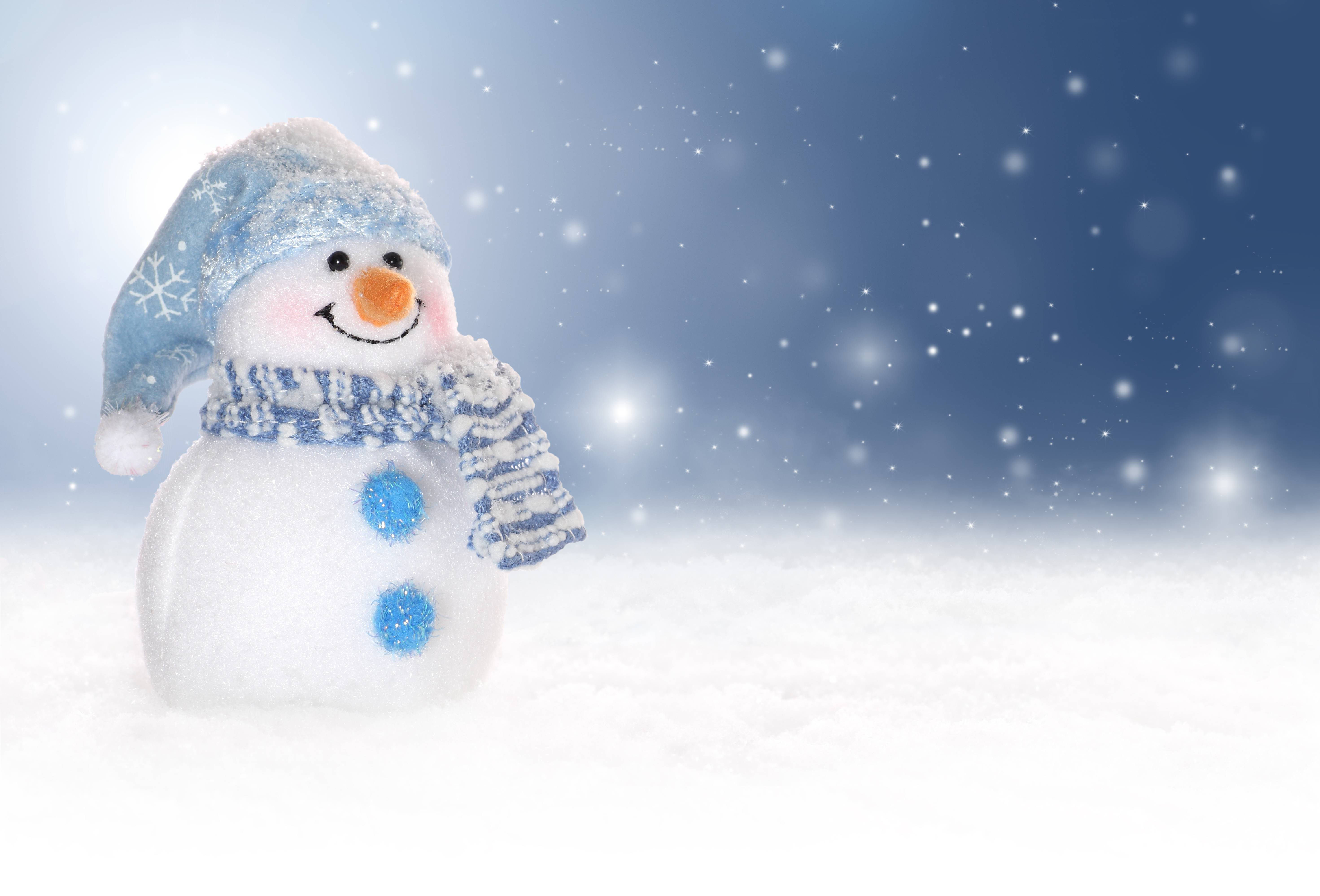 Cute Snow 桌布 壁紙 — 一個戴著藍色帽子和圍巾的快樂雪人站在雪地上，背景是繁星點點的冬夜天空。