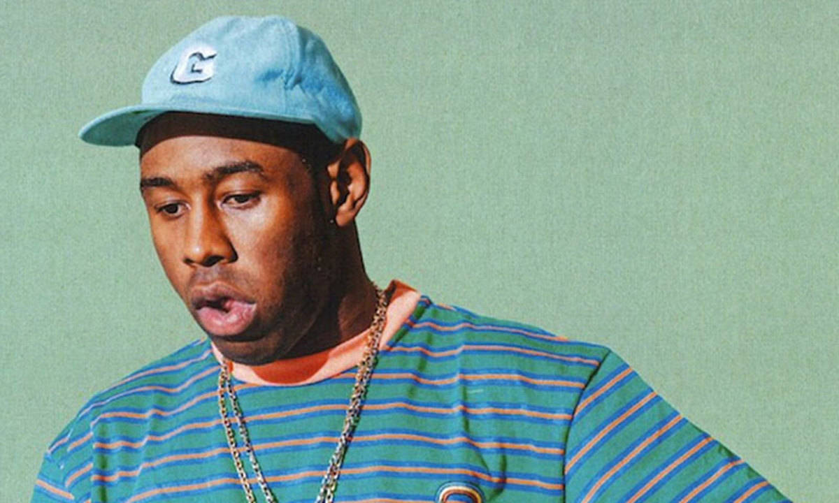90s Rapper 桌布 壁紙 — 一個戴著藍色帽子和條紋襯衫的男人，在柔和的綠色背景下向下看。
