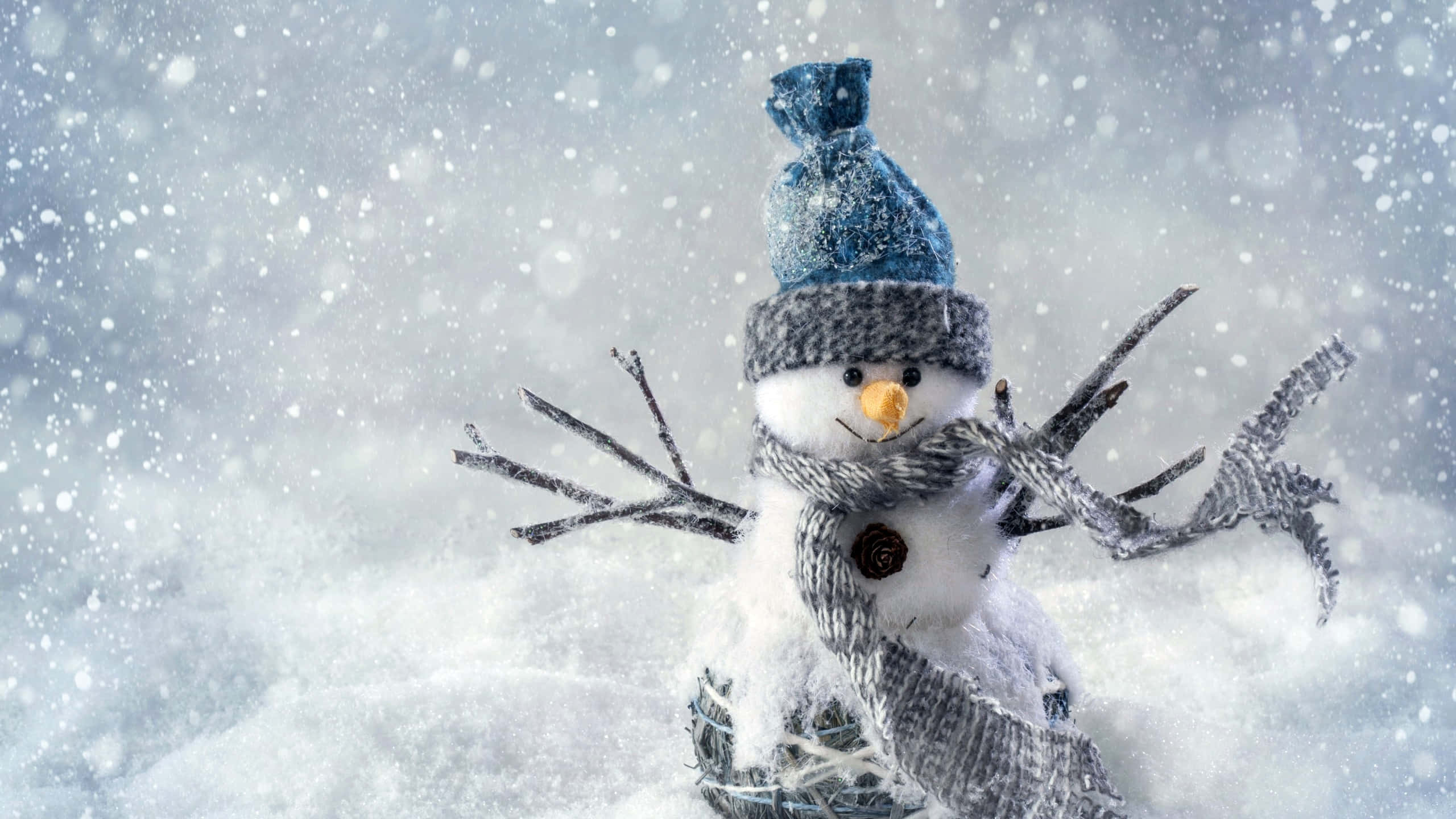 雪人 桌布 壁紙 — 一個戴著藍色帽子和灰色圍巾的快樂雪人站在飄雪中，雪花在它周圍飄落。