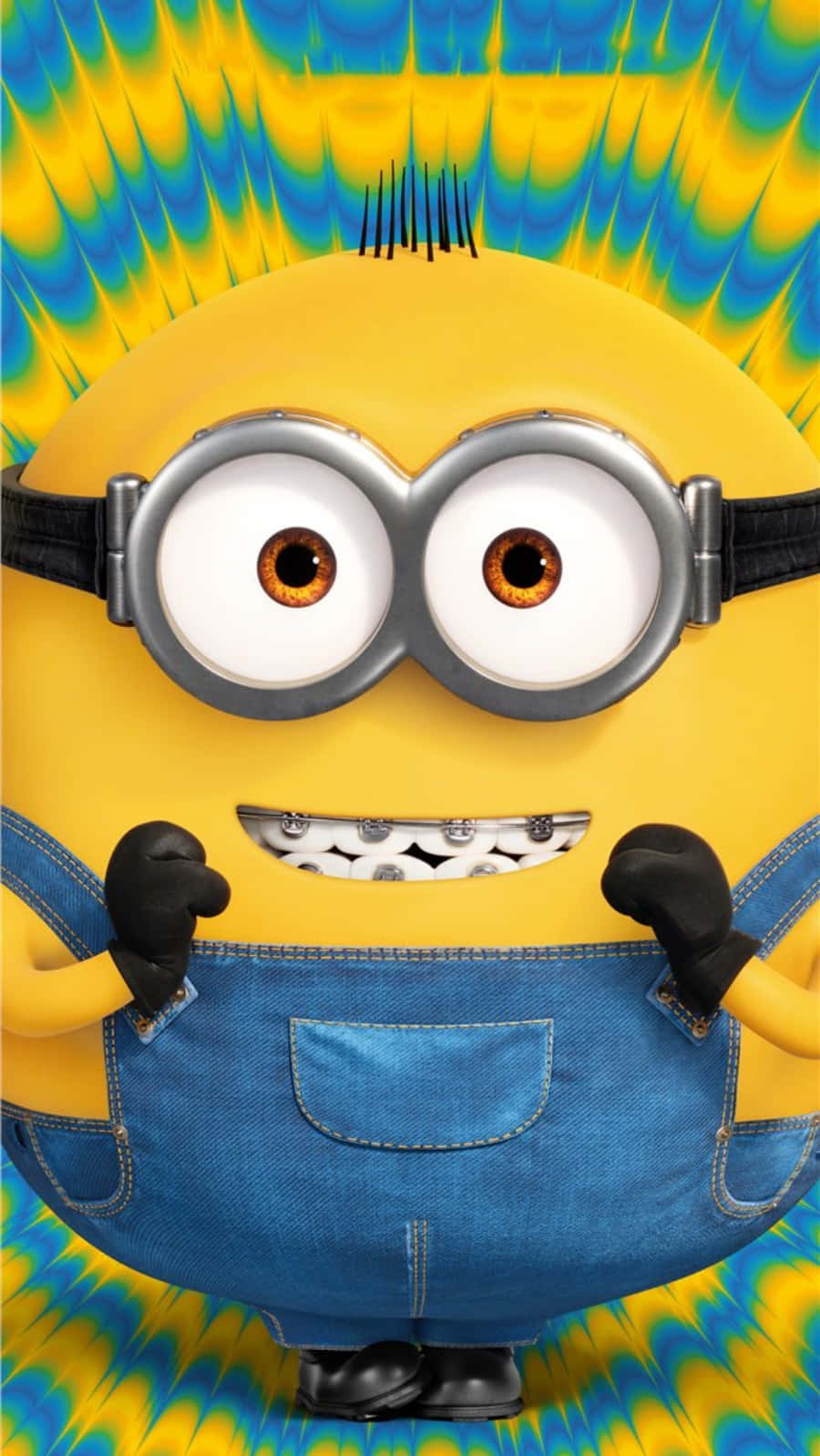 小黃人 桌布 壁紙 — 一個戴著護目鏡和牛仔布工裝褲的開心黃色Minion站在迷幻的藍色和黃色背景前。