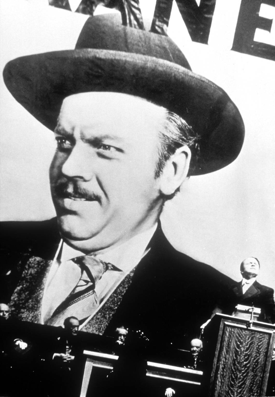 Citizen Kane 桌布 壁紙 — 一個戴著費多拉帽和西裝的男人的黑白特寫，在政治集會上表情嚴肅。