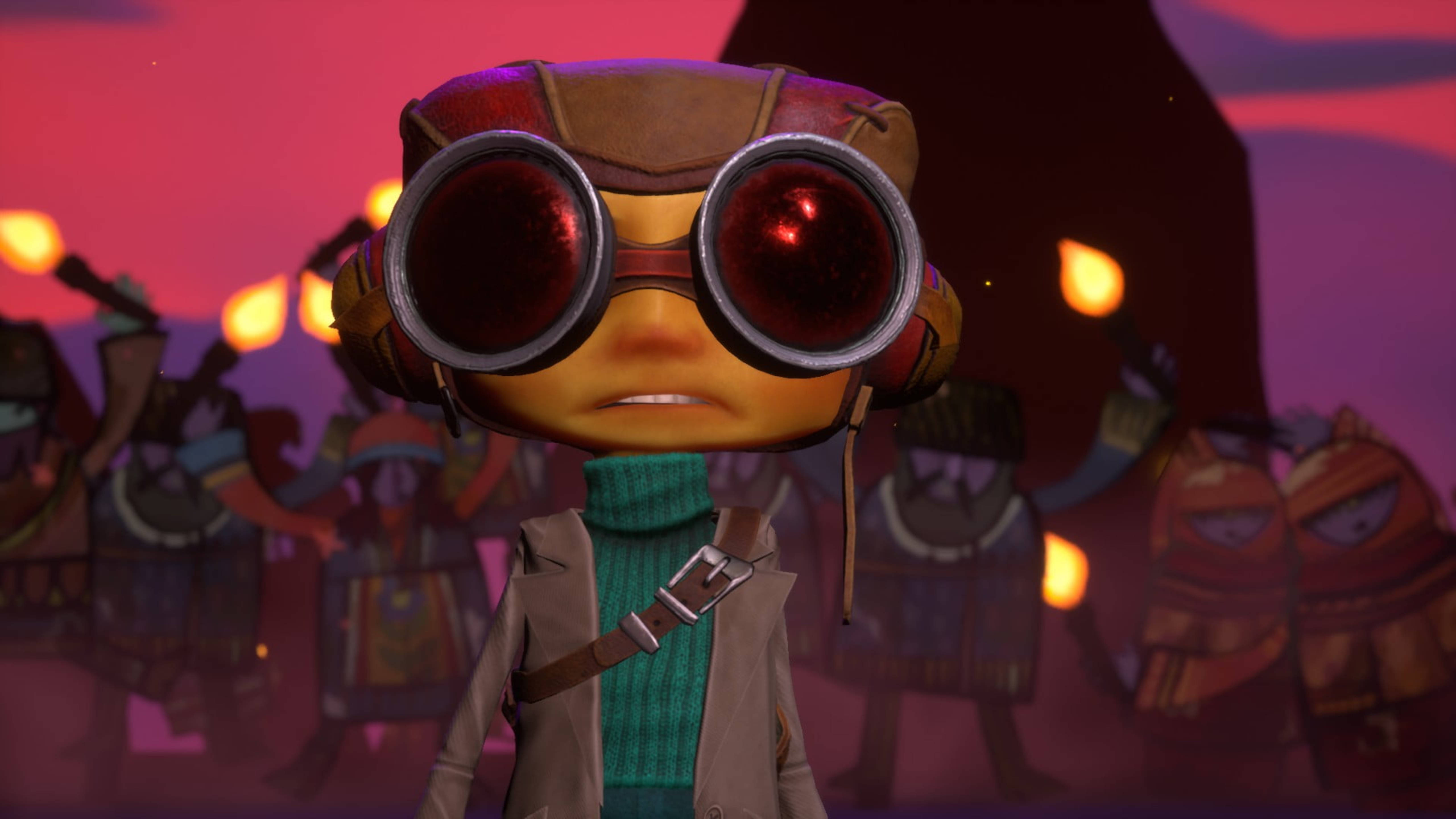 Psychonauts 桌布 壁紙 — 一個戴著超大護目鏡和綠色高領毛衣的小型動畫角色，在黃昏時分站在一群手持火把的人群面前。