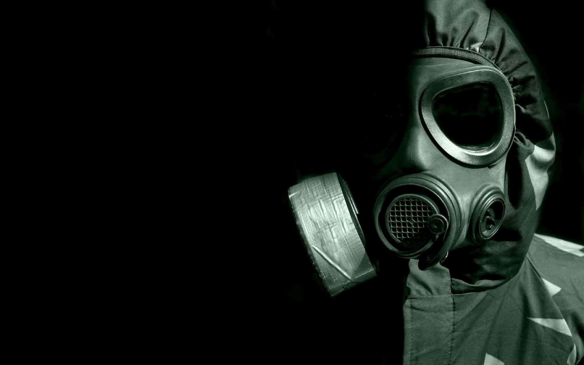 Unsettling 桌布 壁紙 — 一個戴著軍用防毒面具和頭罩的人從黑暗中出現，單一聚光燈突顯了面具的陰森細節。