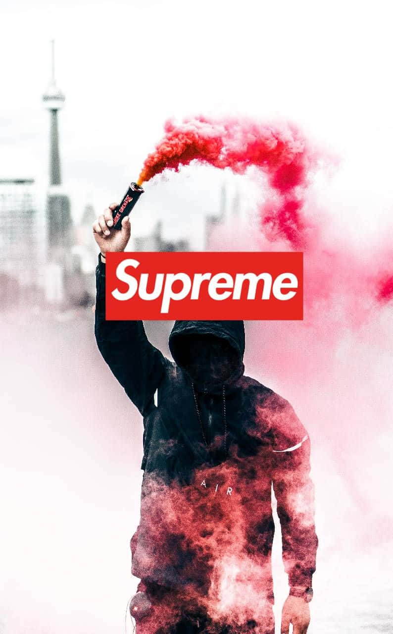 supreme 桌布 壁紙 — 一個戴著連帽的人物在模糊的城市景觀中手持紅色信號火炬，並疊加了Supreme標誌。
