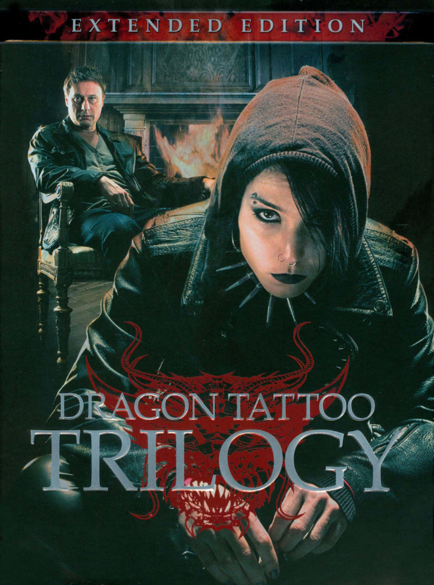 Tattoo Girl 桌布 壁紙 — 一個戴著連帽衫、化著深色妝容的女人強烈地凝視著，而一個男人坐在熊熊燃燒的壁爐旁邊的椅子上。