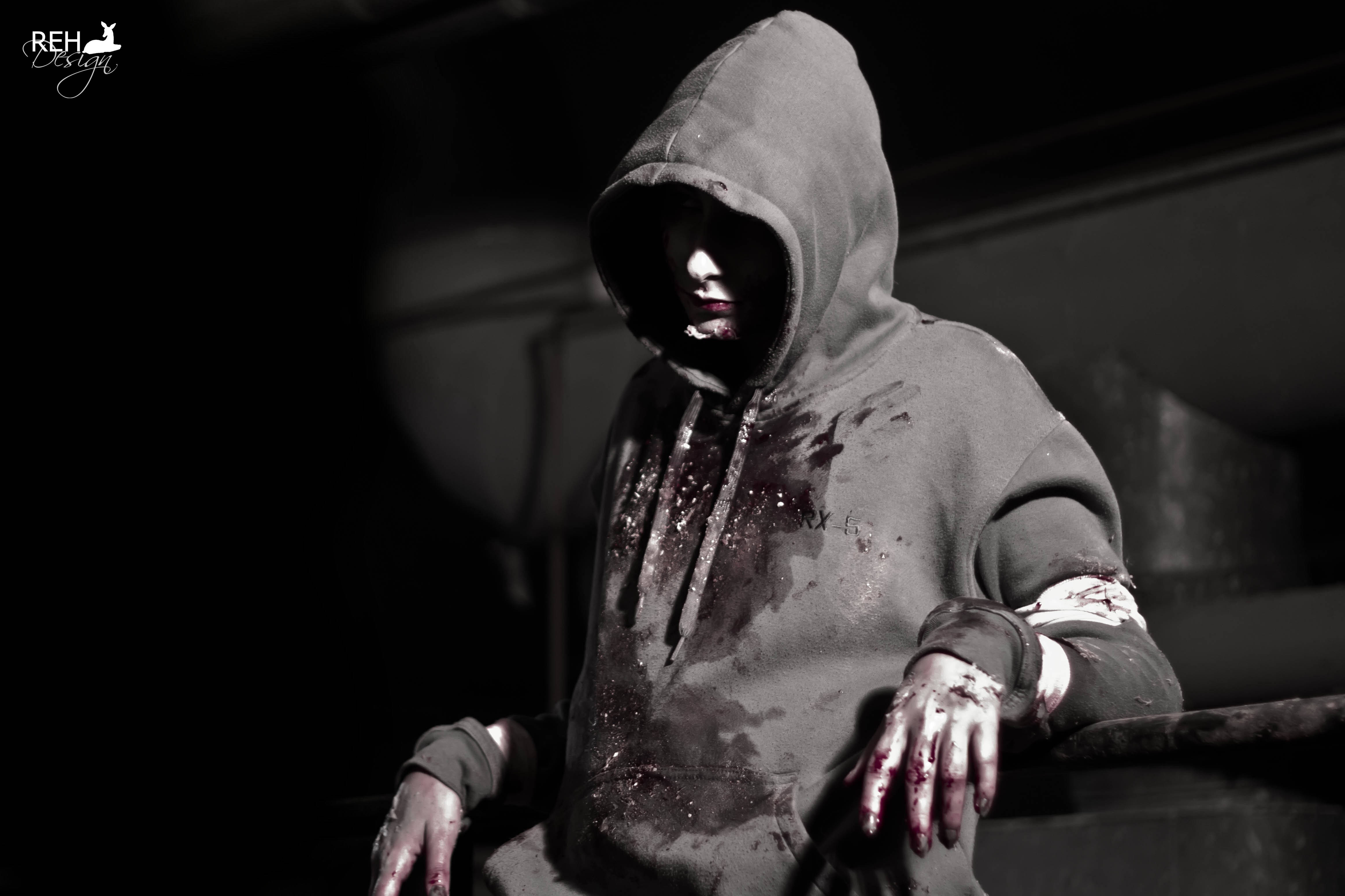 dead 桌布 壁紙 — 一個戴著連帽衫、雙手沾滿鮮血的人物坐在光線昏暗、陰影重重的環境中。