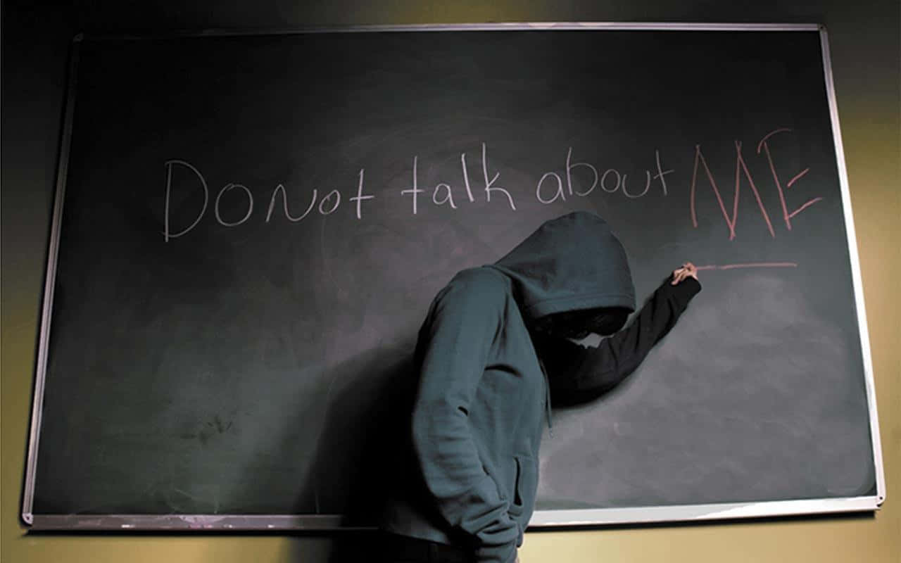 emo 桌布 壁紙 — 一個戴著連帽衫的人影在昏暗的教室裡用紅色粉筆在黑板上寫下「Do not talk about ME」。
