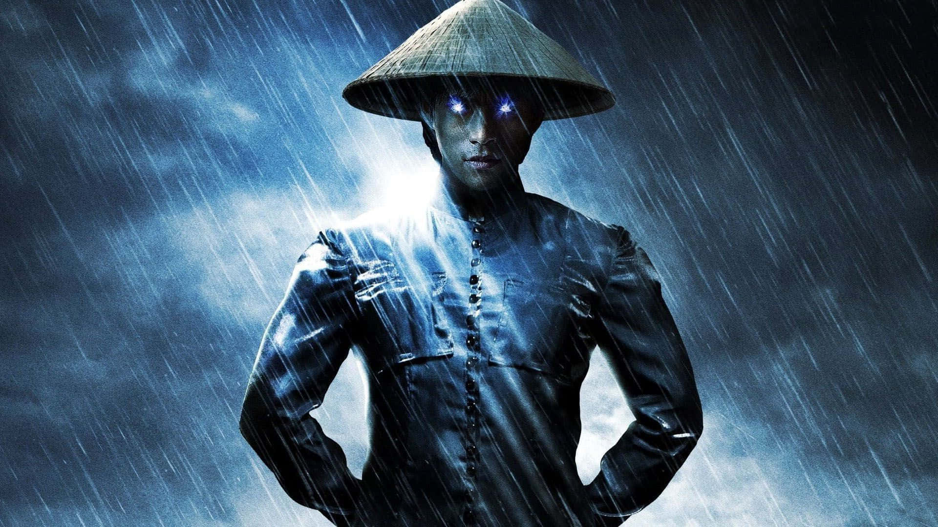 Mortal Kombat Raiden 桌布 壁紙 — 一個戴著錐形帽的神秘人物，在傾盆大雨中帶著發光的眼睛和戲劇性的背光，挑釁地站立。