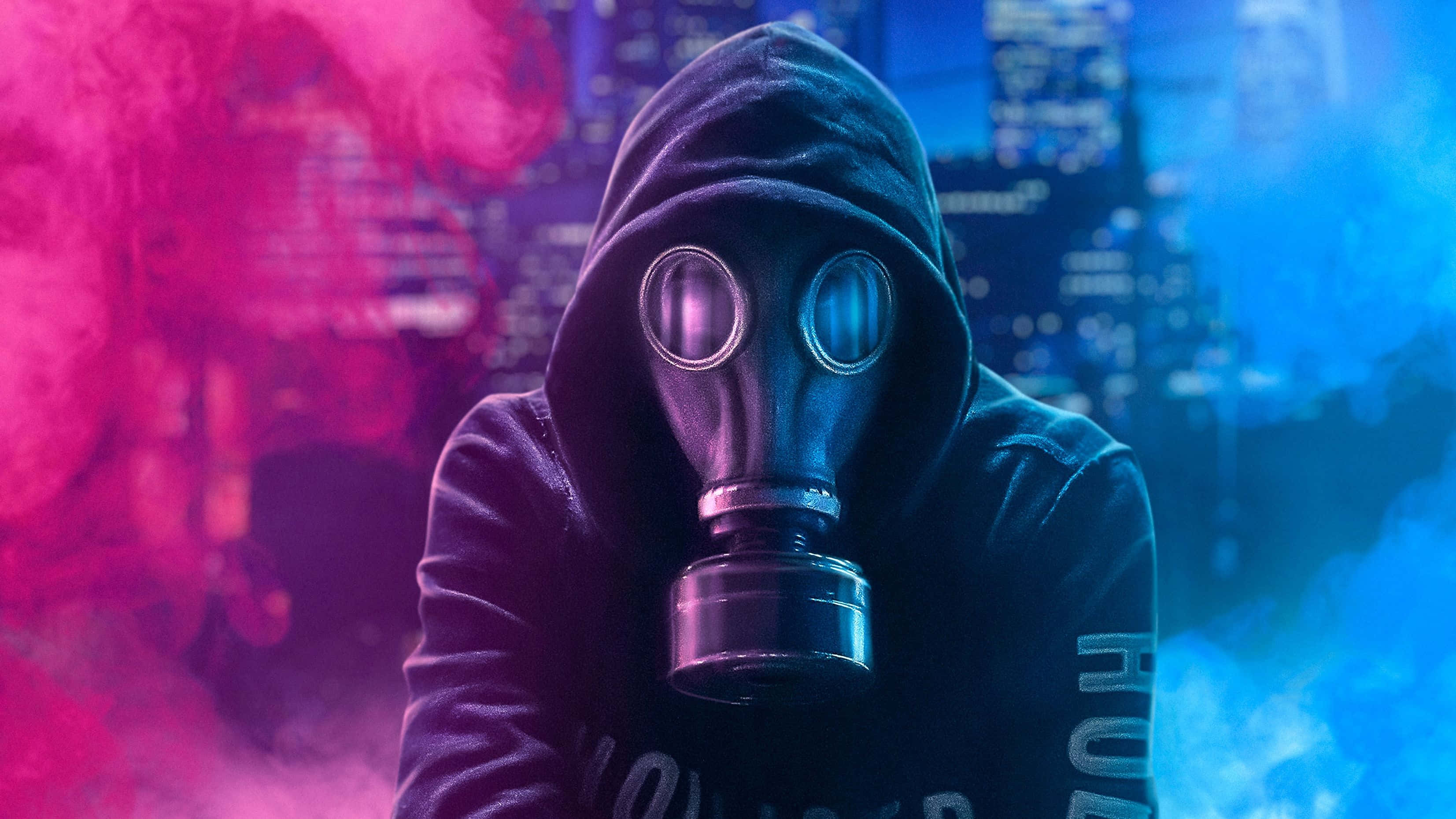 Mask 桌布 壁紙 — 一個戴著防毒面具和連帽衫的人物站在霓虹粉紅和藍色煙霧中，背景是模糊的城市景觀。