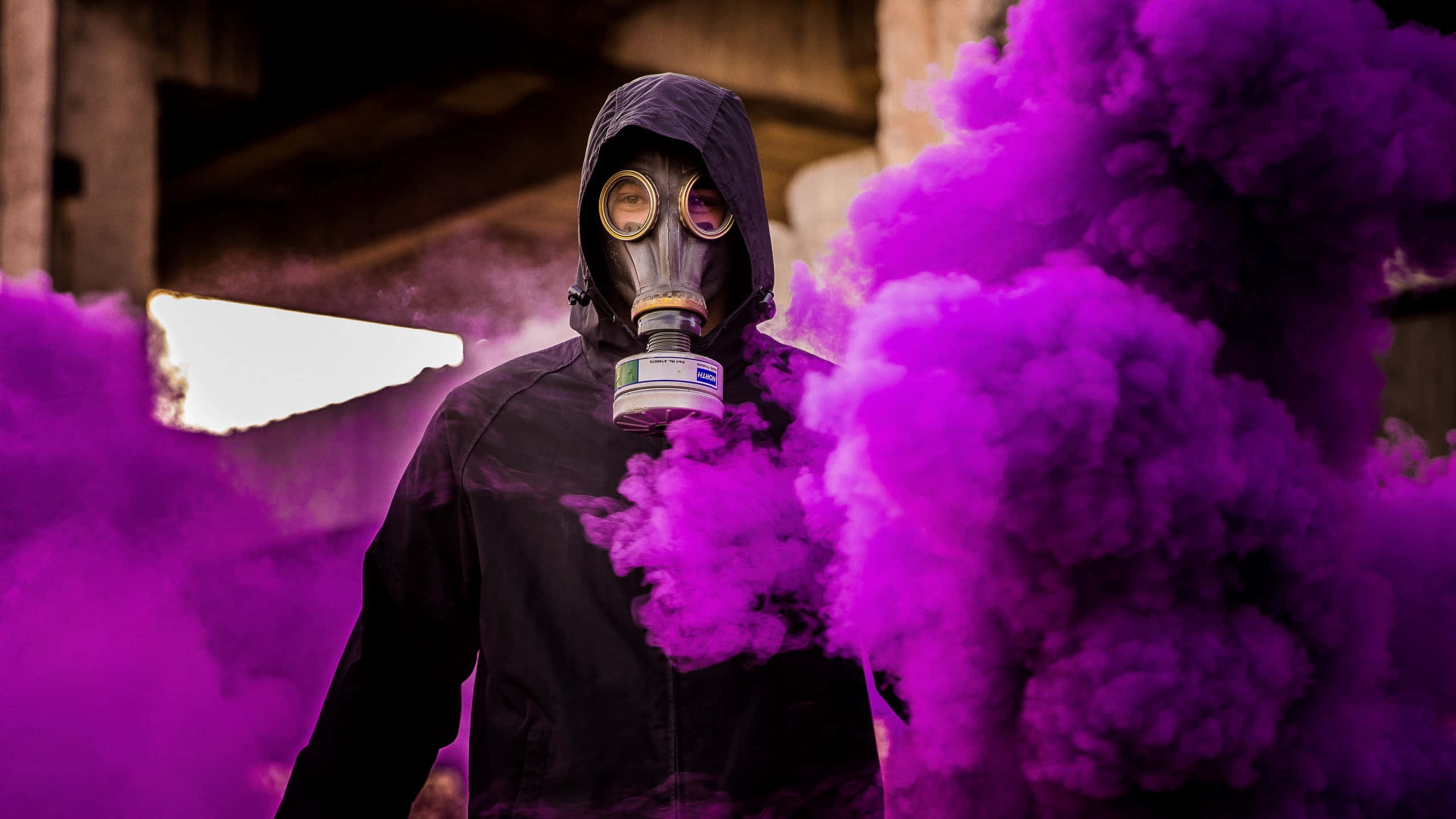 Gas Mask 桌布 壁紙 — 一個戴著防毒面具和黑色頭罩的人，站在昏暗工業廢墟中旋轉的鮮豔紫色煙霧中。