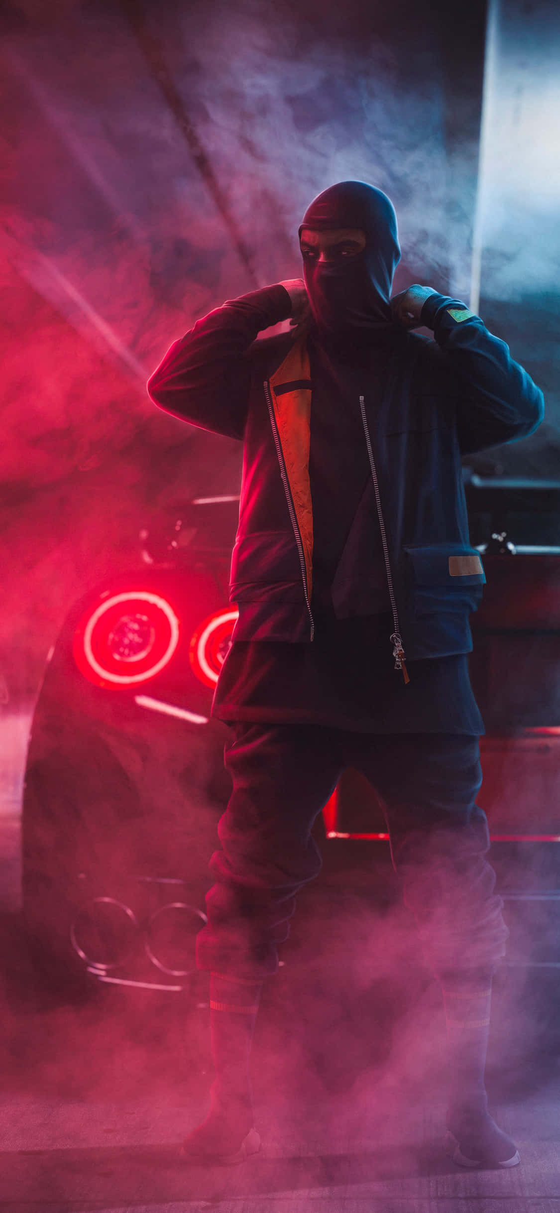 Ski Mask 桌布 壁紙 — 一個戴著面具、身穿深色連帽衫的人自信地站在一輛發光的紅色跑車旁邊，周圍是煙霧彌漫的霓虹燈陰影。