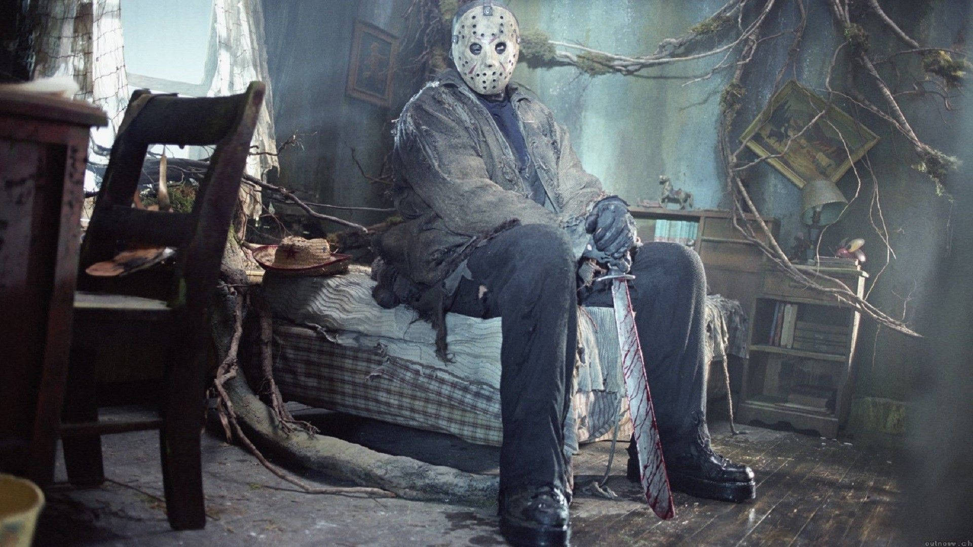 恐怖角色 Jason Voorhees 坐在破舊小屋的床上，手持一把血淋淋的砍刀。 — 十三號星期五 GIF 壁紙