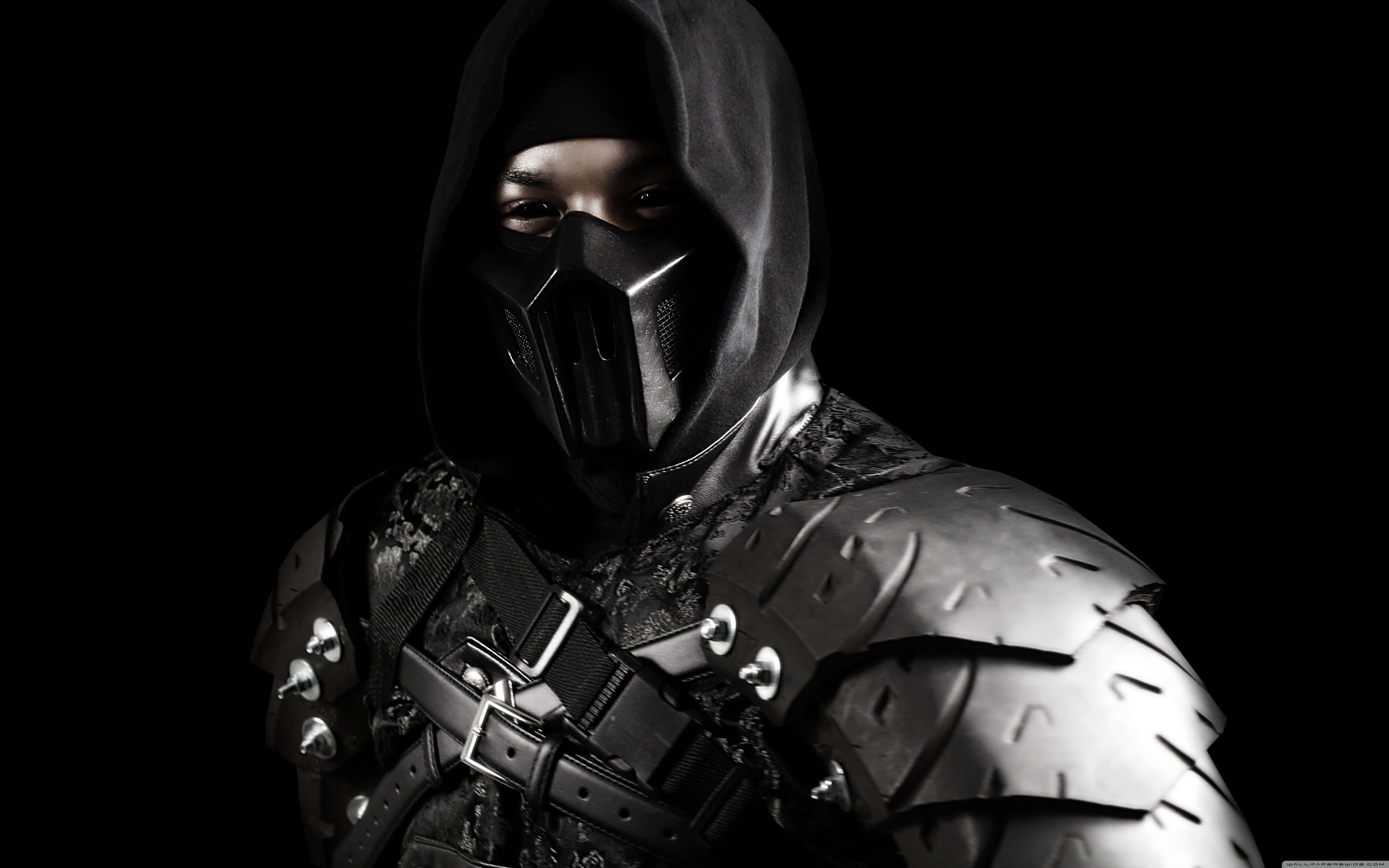 Mortal Kombat Noob Saibot 桌布 壁紙 — 一個戴著頭罩、身穿暗色盔甲和面具的戰士，在黑色背景下強烈地凝視著。