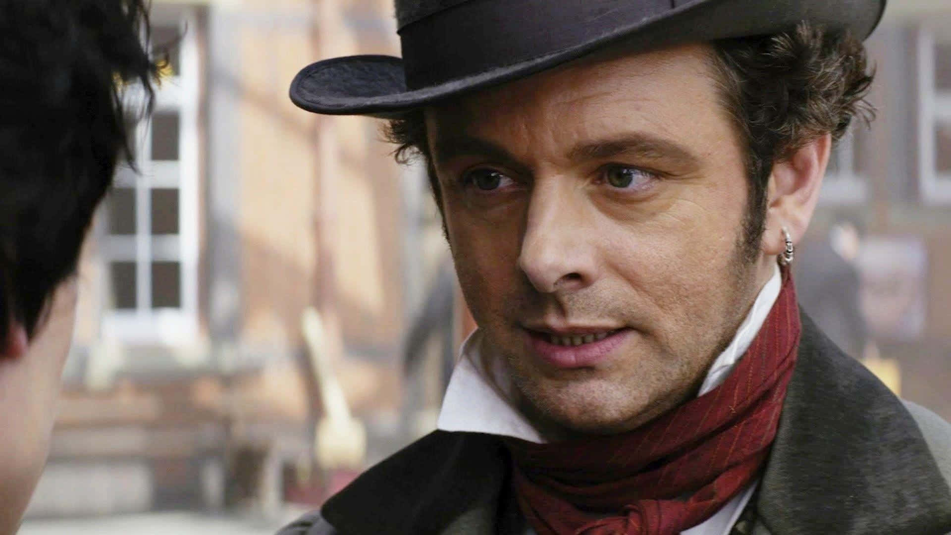 Michael Sheen 桌布 壁紙 — 一個戴著高帽和紅色圍巾的男人在歷史街道場景中專注地看著另一個人。