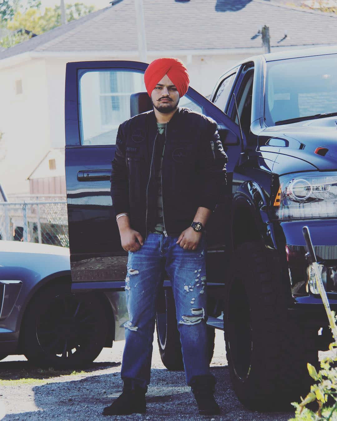 戴紅色頭巾的男人站在黑色皮卡車旁 — Sidhu Moose Wala 壁紙