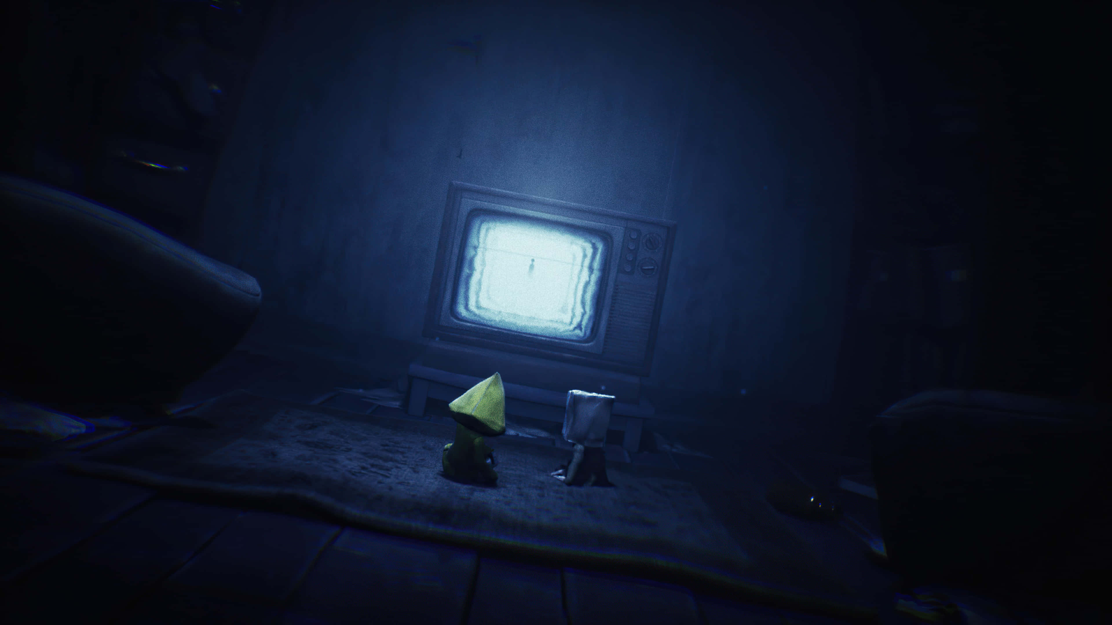 Little Nightmares 4K 桌布 壁紙 — 一個戴著黃色連帽的小身影坐在黑暗的房間裡，面對著發光的電視螢幕。