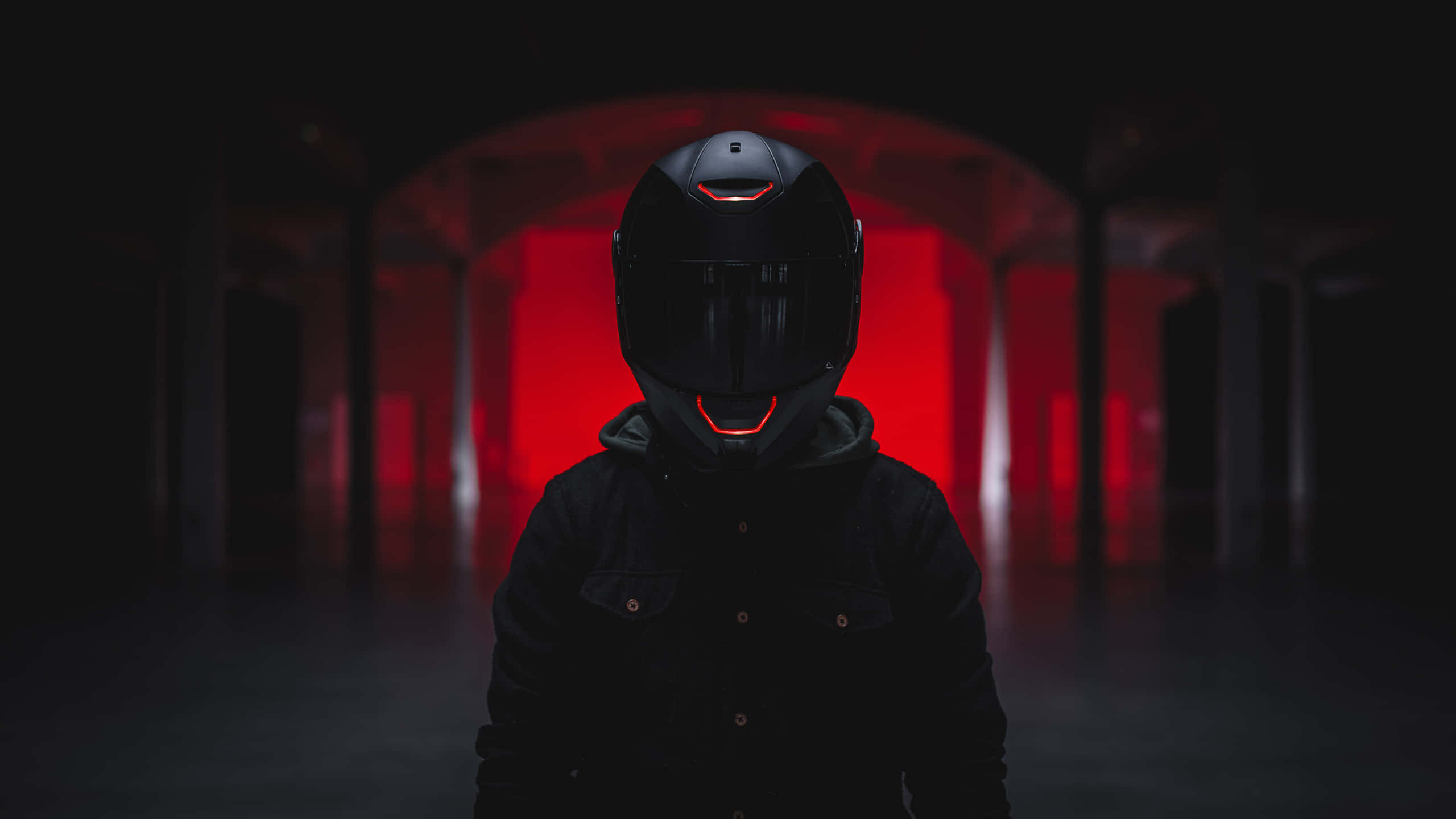 biker 桌布 壁紙 — 一個戴著黑色機車安全帽的人站在一條黑暗的隧道中，身後有發光的紅燈照亮。